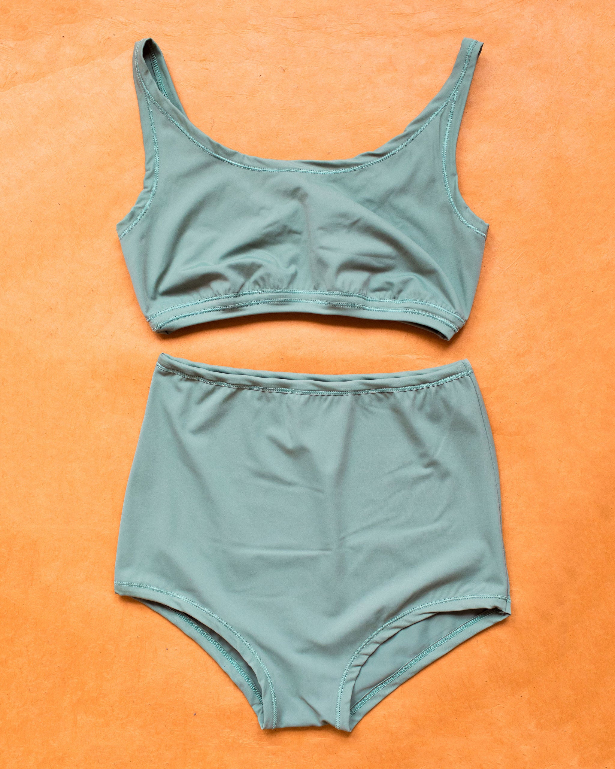 Flat lay of Swimwear Sky Rise Bottoms and Top set in Lichen Green.