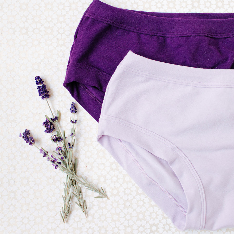 Flat lay on a white patterned surface with lavender nearby of Hipster style Light Lavender and Amethyst solid colors.