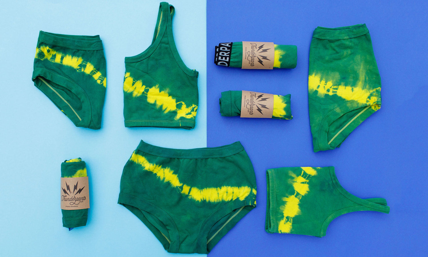 Flat lay of multiple Thunderpants styles in Lighting Bolt hand dye - green/blue color with yellow stripe. 