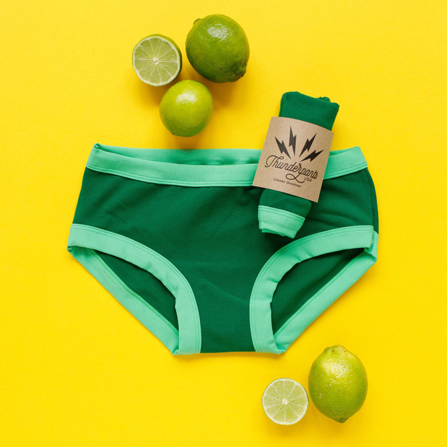 Flay lay of packaged Thunderpants underwear with limes around.