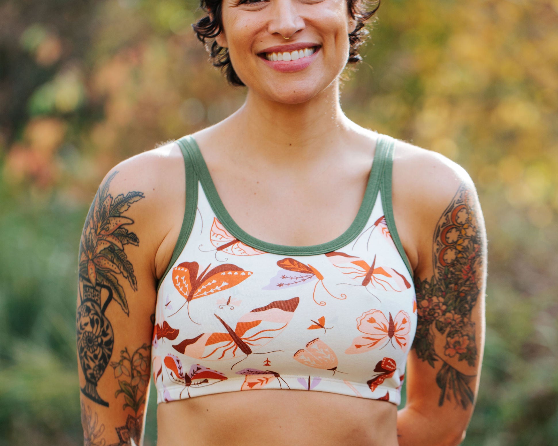 Model wearing Thunderpants Longline Bra in Field Study: a moth print in red, orange, pink, and purple bound in green.