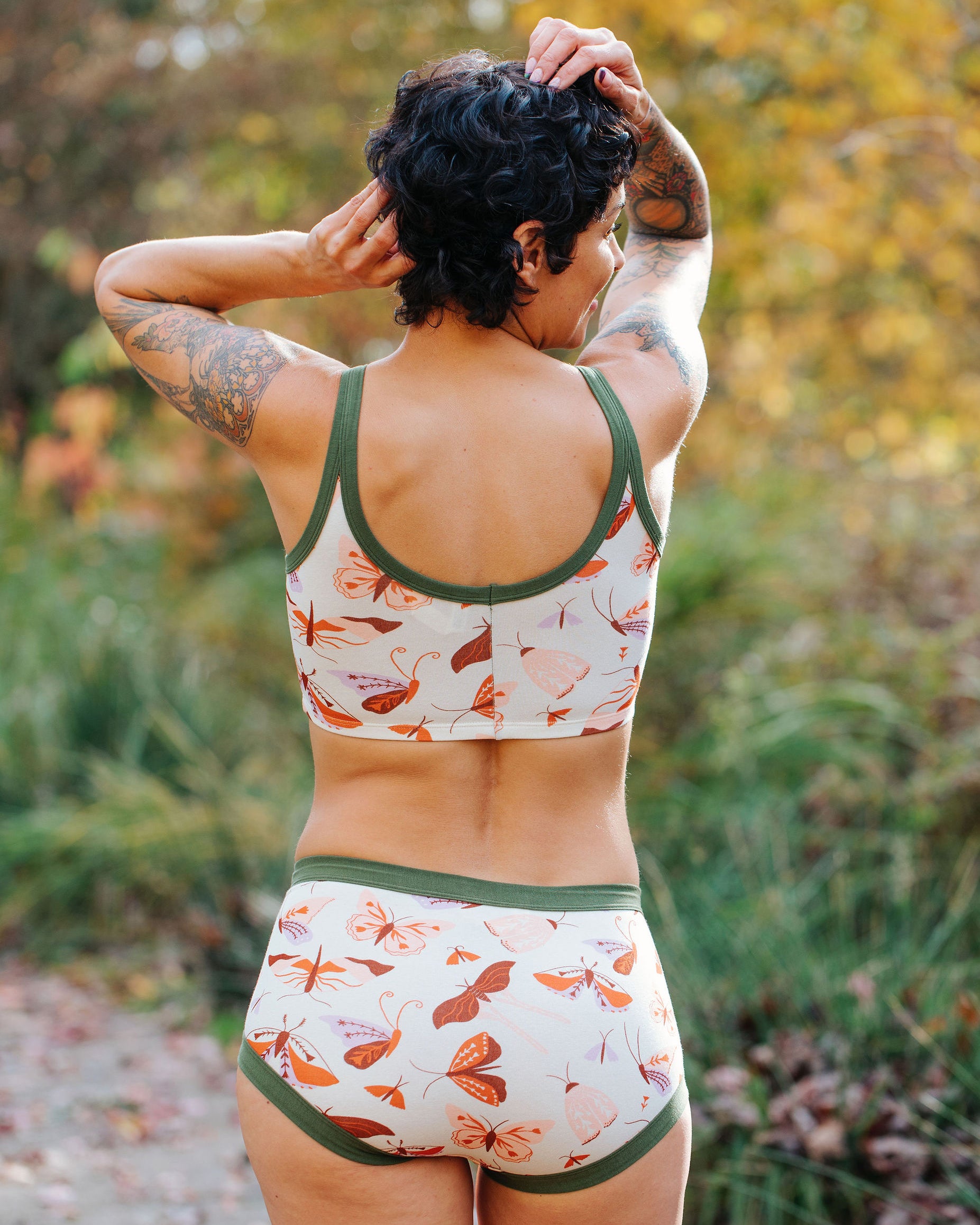 Model wearing Thunderpants Longline Bra and Original style underwear in Field Study: a moth print in red, orange, pink, and purple bound in green.