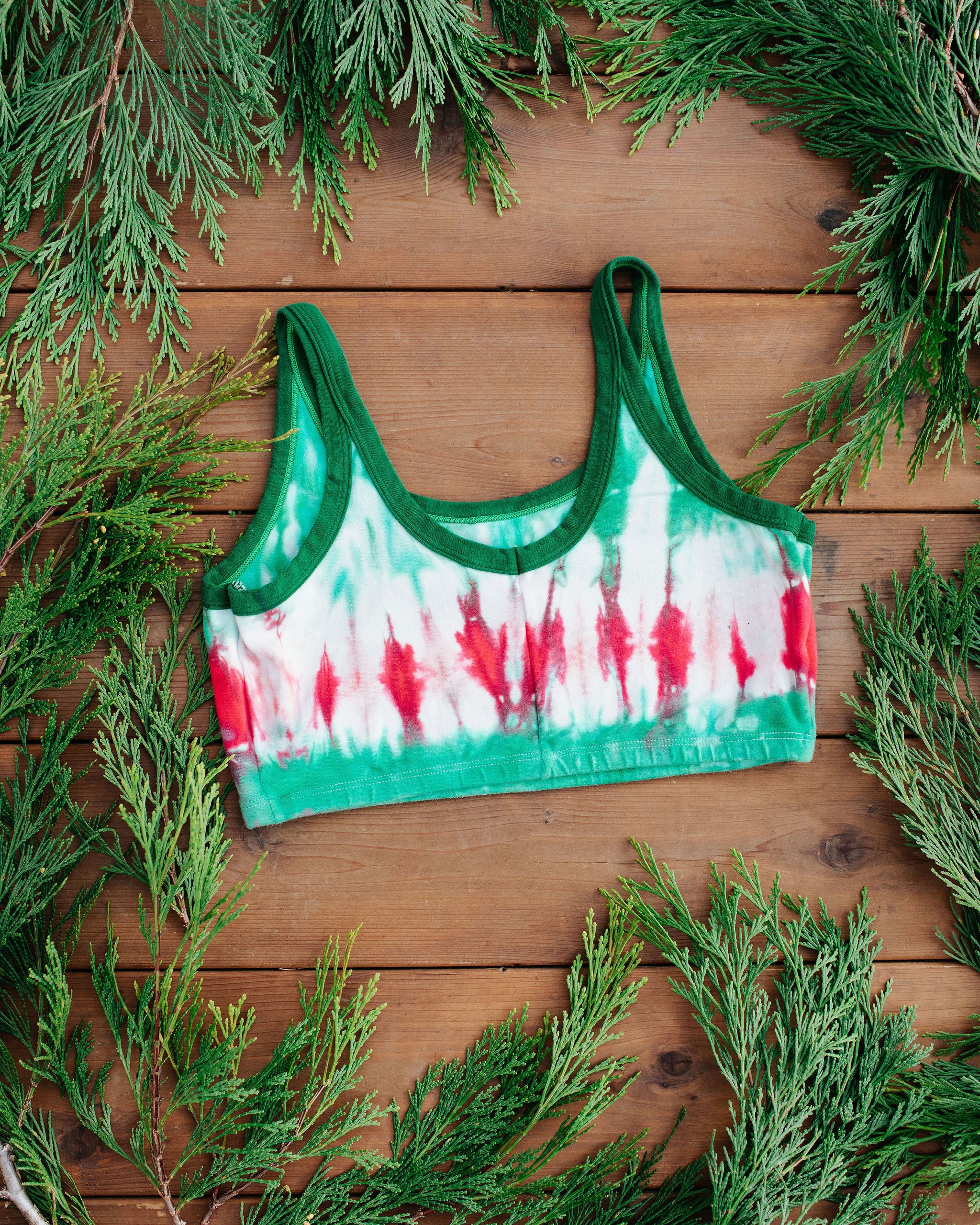 Flat lay of Thunderpants Longline Bra in Holiday Dye - red and green tie dye with green binding. 
