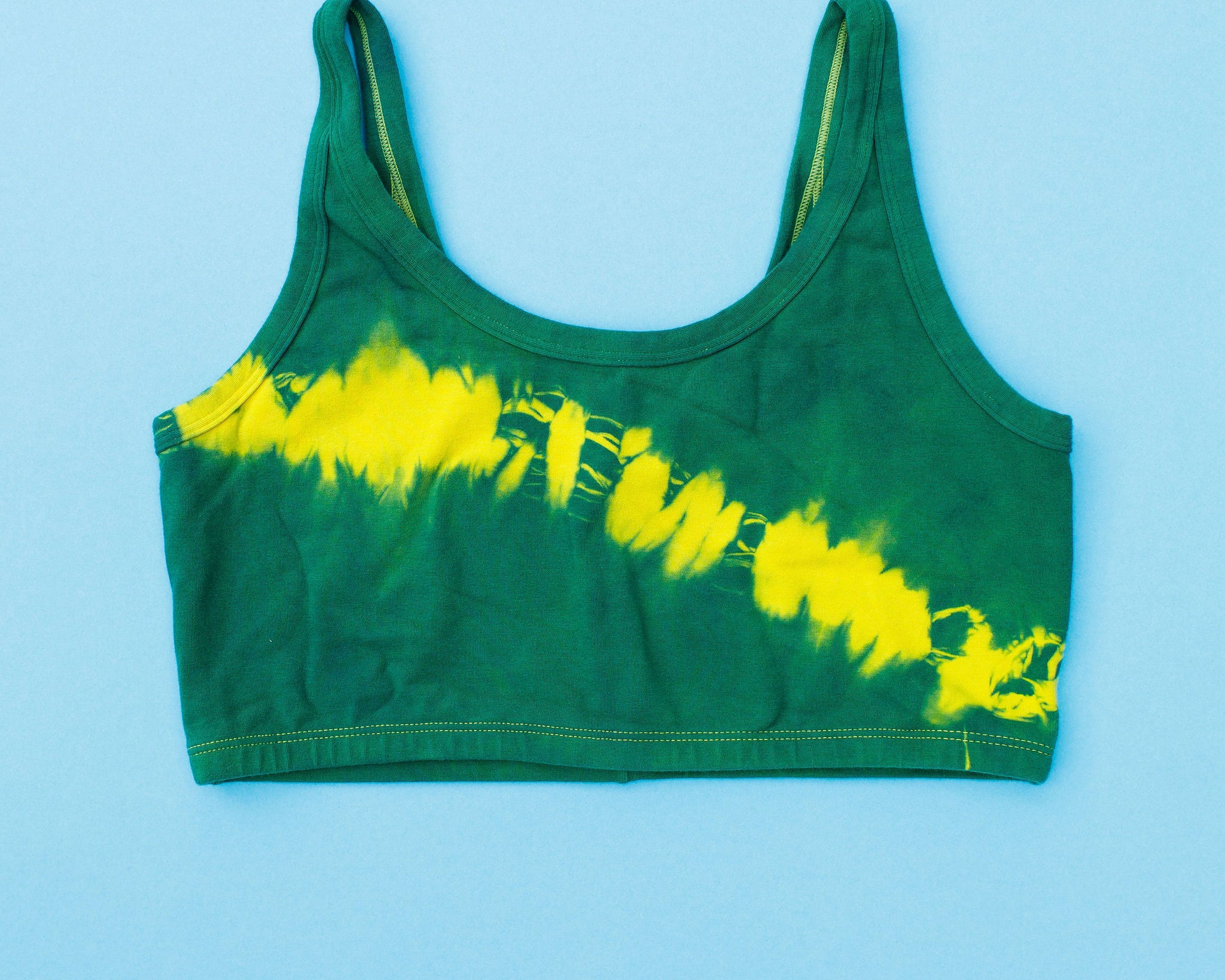 Flat lay of Thunderpants Longline Bra in Lightning Bolt Hand Dye - blue/green with yellow stripe.