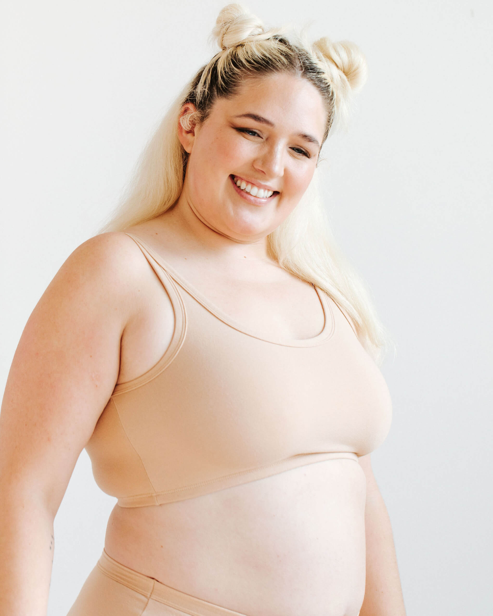 Close up of model wearing Thunderpants Longline Bra in Pine Nut - lighter tan color.