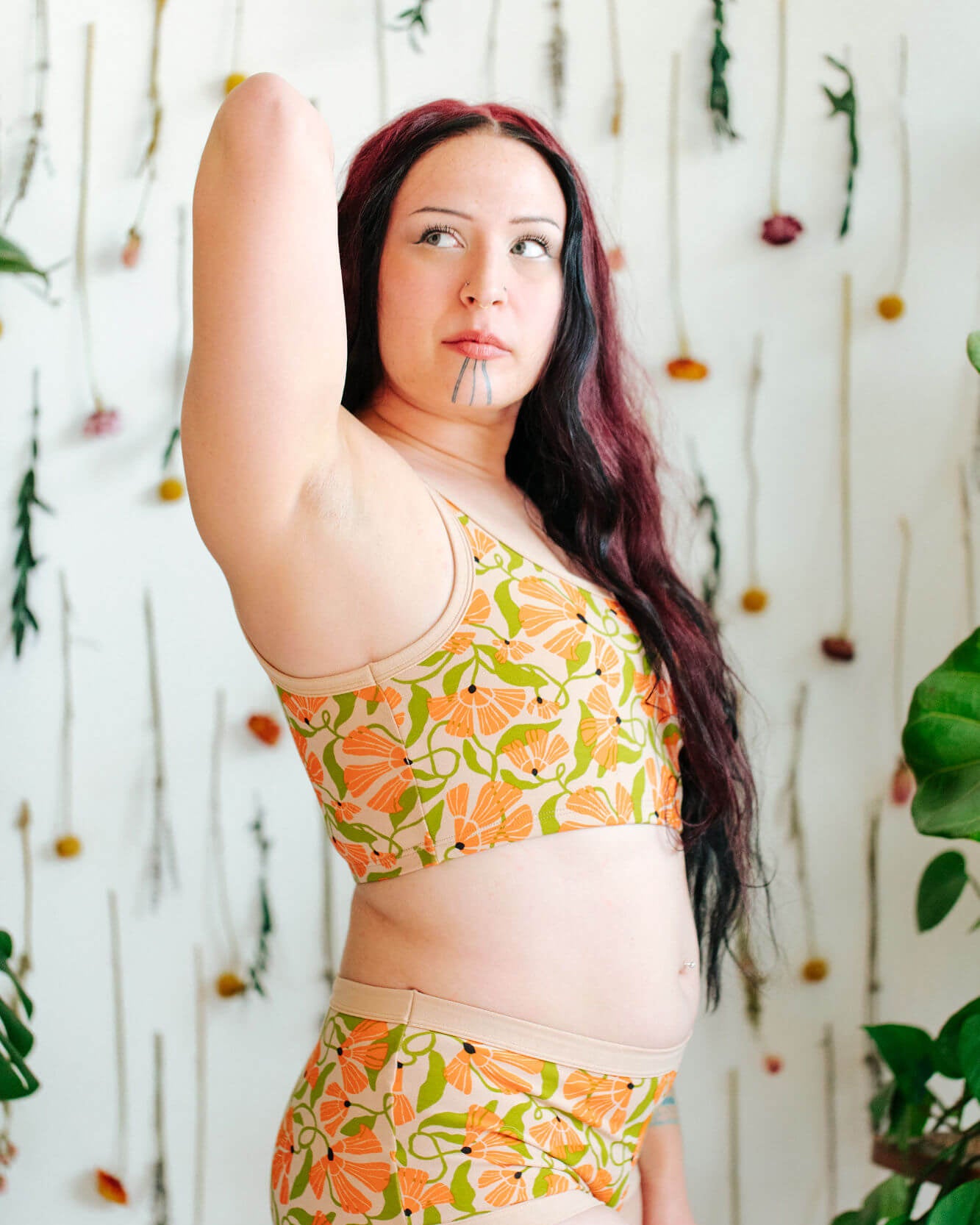 Model wearing a set of Thundrpants Longline Bra and Original style underwear in Secret Garden - orange flowers and green leaves.