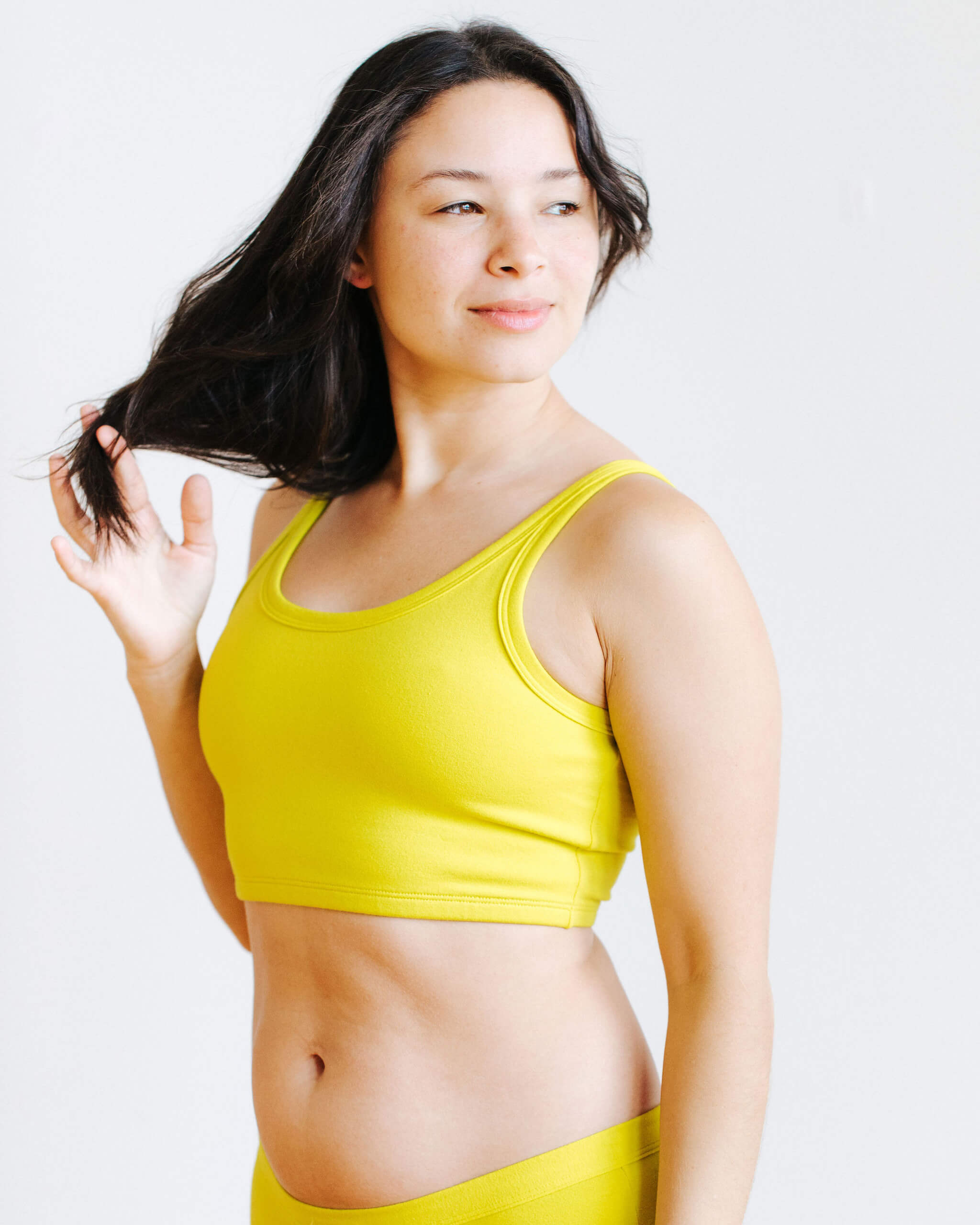Model wearing Thunderpants Longline Bra in Star Fruit color - a chartreuse yellow.