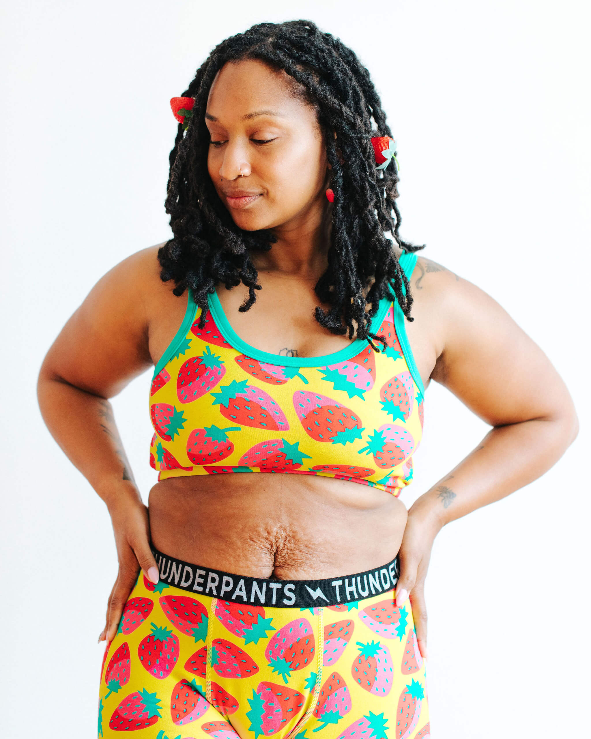 Model wearing Thunderpants Longline Bra in a Strawberry print - pink, red, and peacock green on chartreuse. 