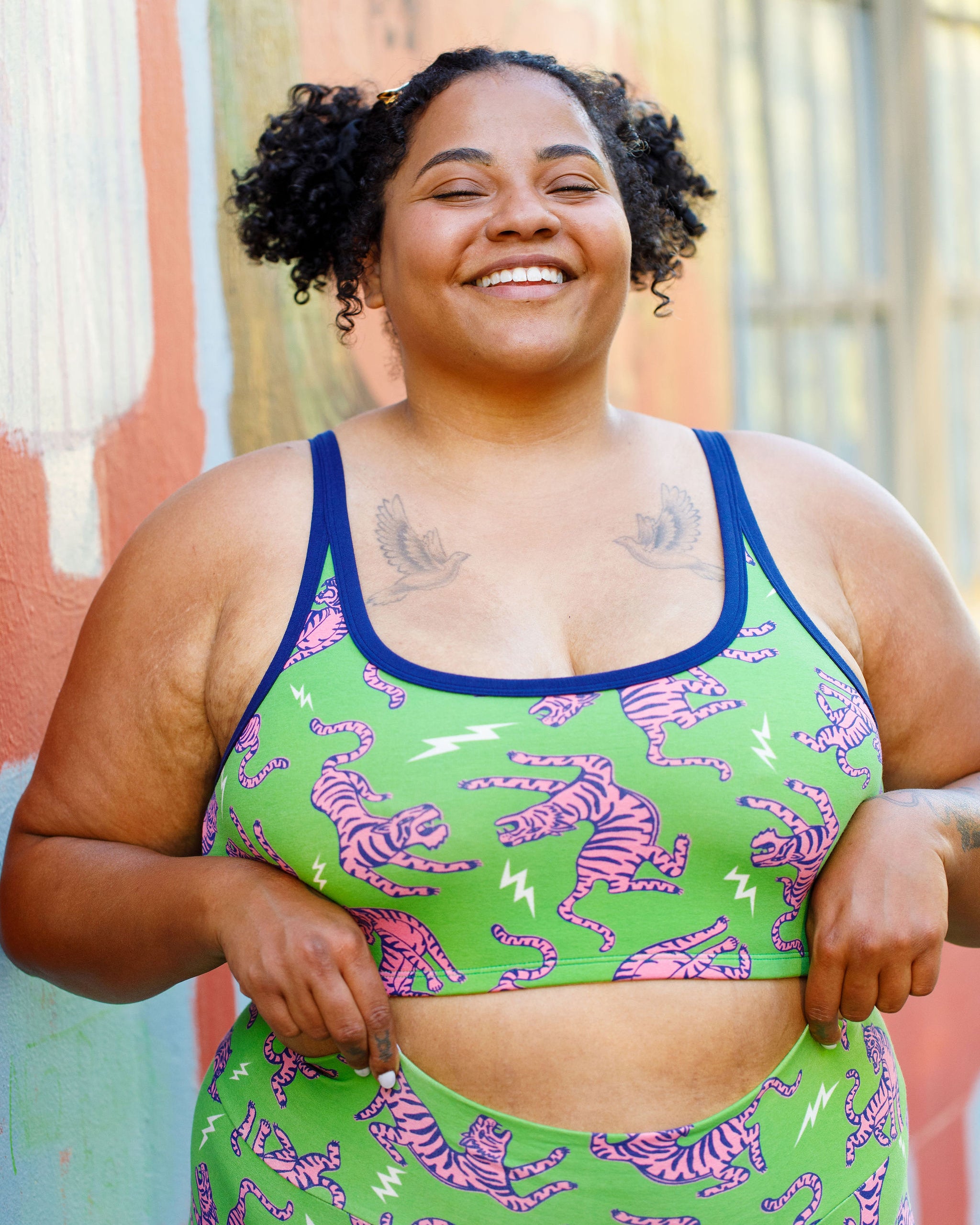 Model wearing Thunderpants organic cotton Longline Bra in Electric Tiger - green with pink and blue tigers and white lightning bolts.