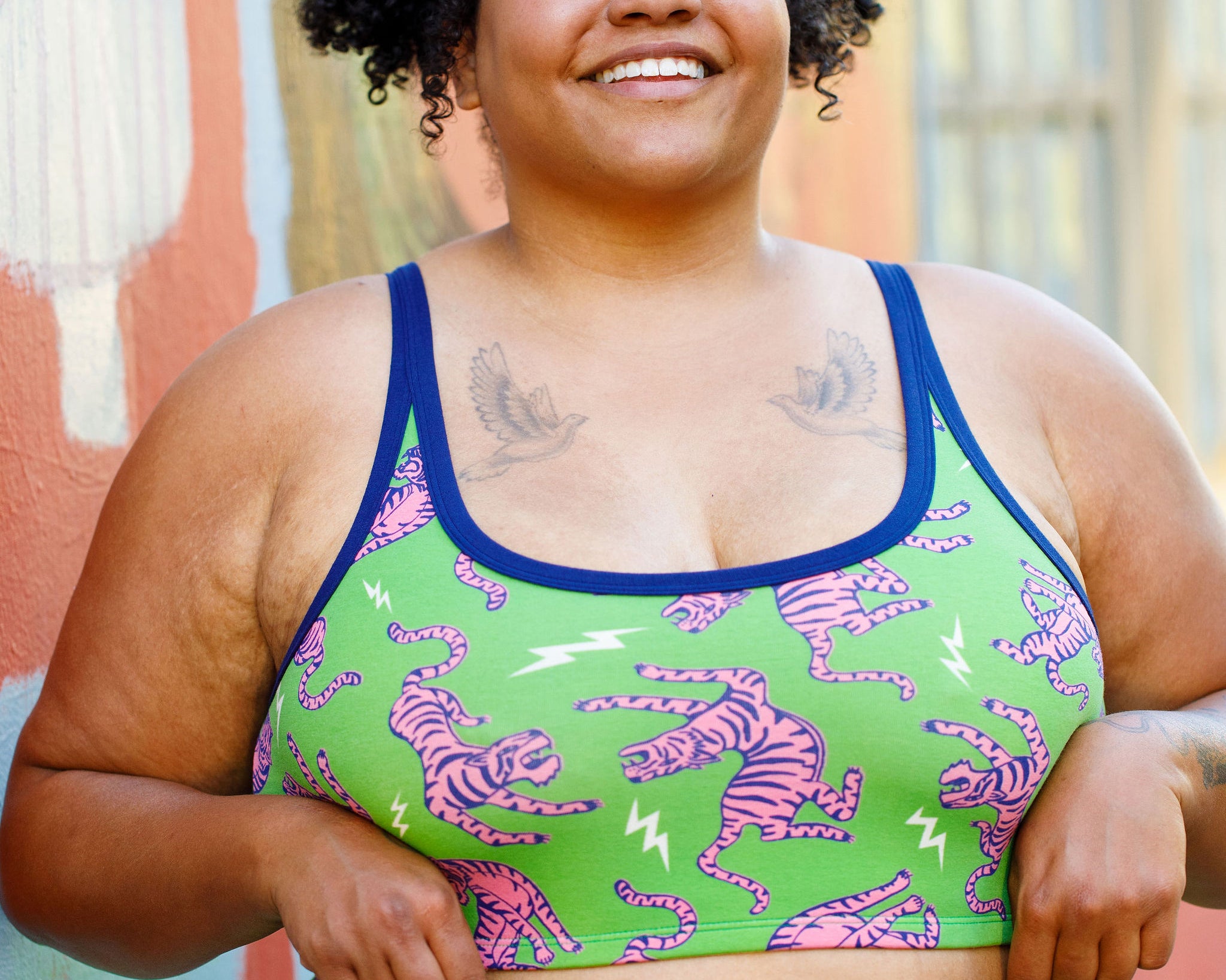 Model wearing Thunderpants organic cotton Longline Bra in Electric Tiger - green with pink and blue tigers and white lightning bolts.