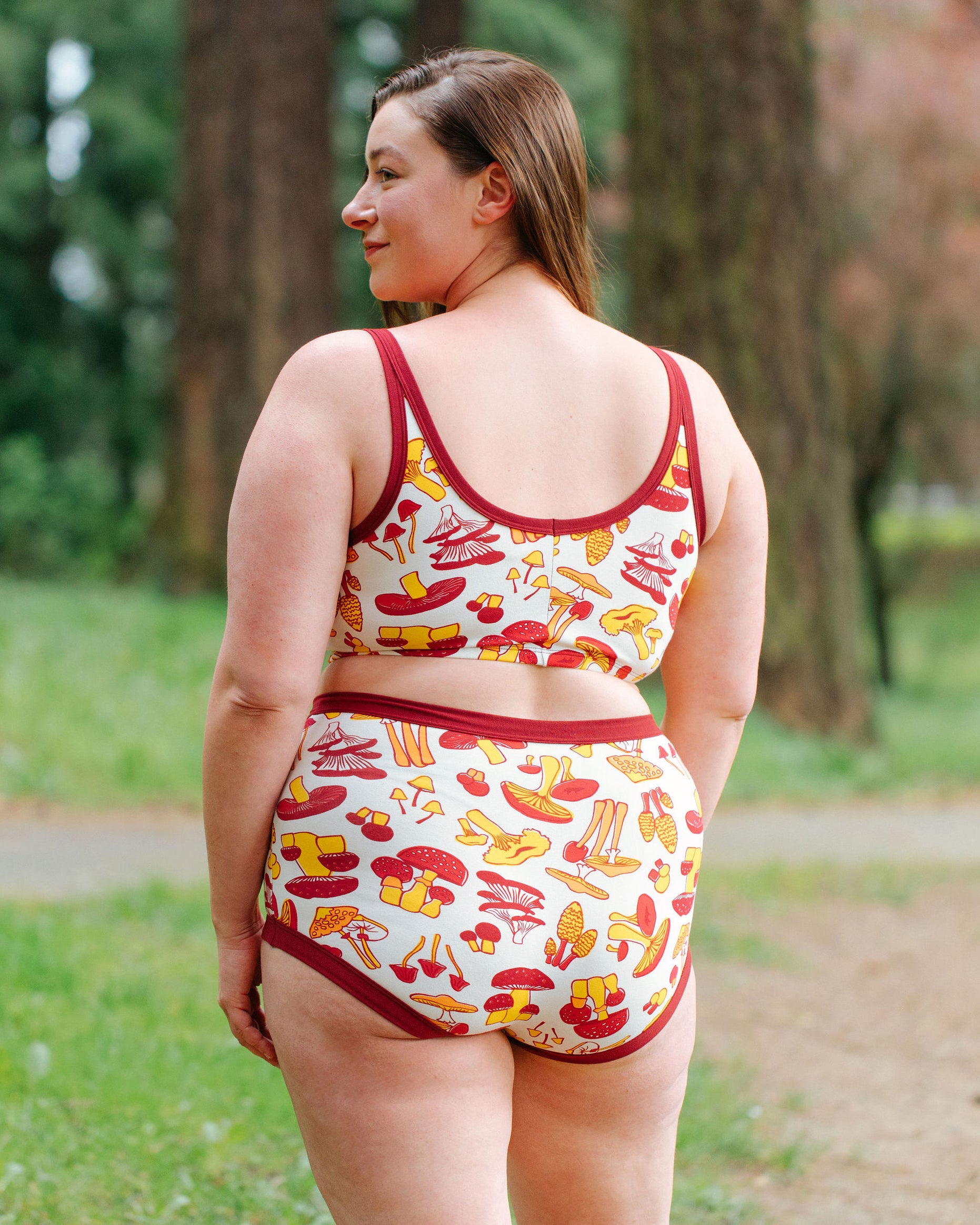 A model wearing Thunderpants Longline Bra and Sky Rise style underwear and underwear in Whadda Fungi - red, yellow, and orange mushroom print.