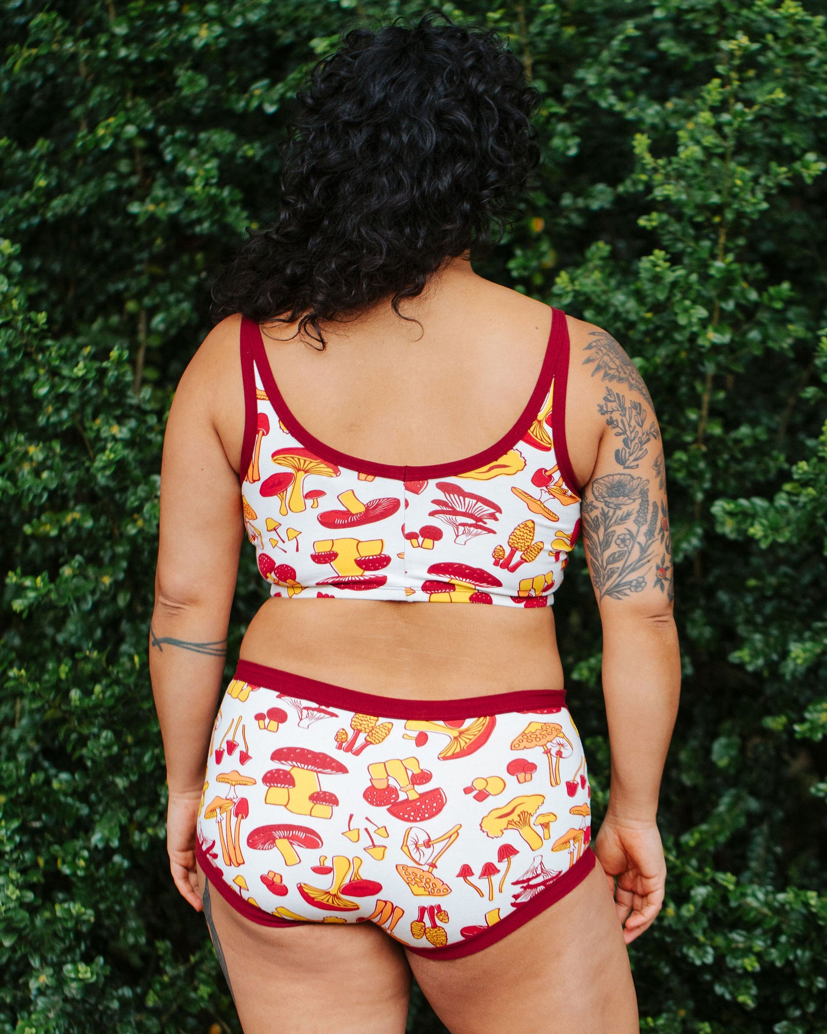 A model wearing Thunderpants Longline Bra and Original style underwear in Whadda Fungi - red, yellow, and orange mushroom print.