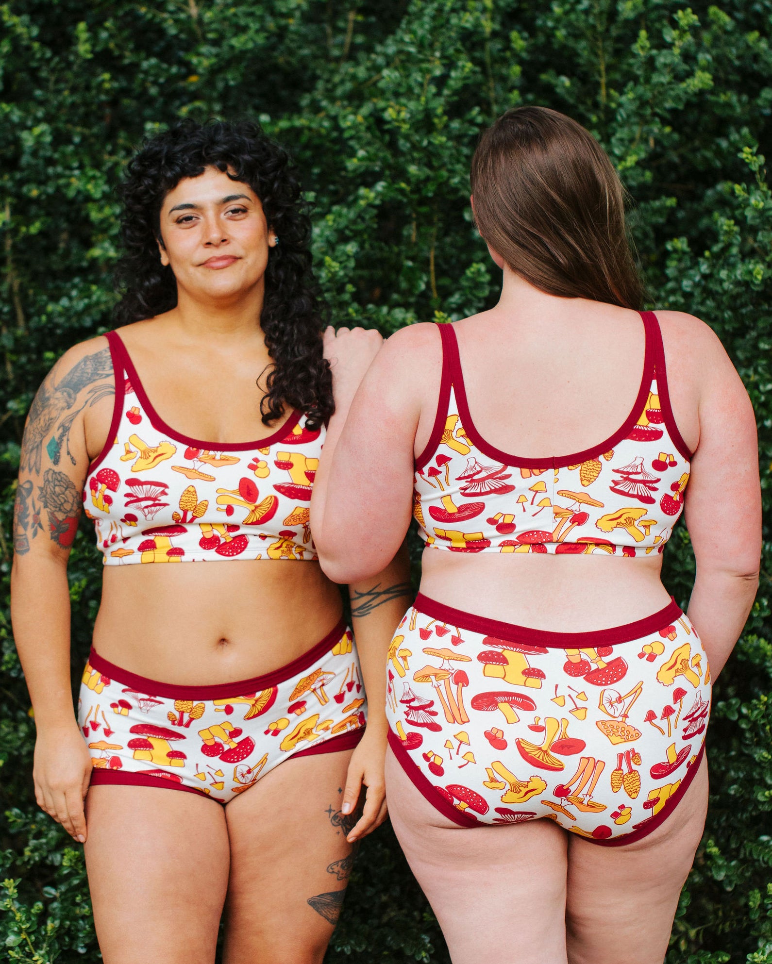Two models wearing Thunderpants Longline Bras and underwear in Whadda Fungi - red, yellow, and orange mushroom print.