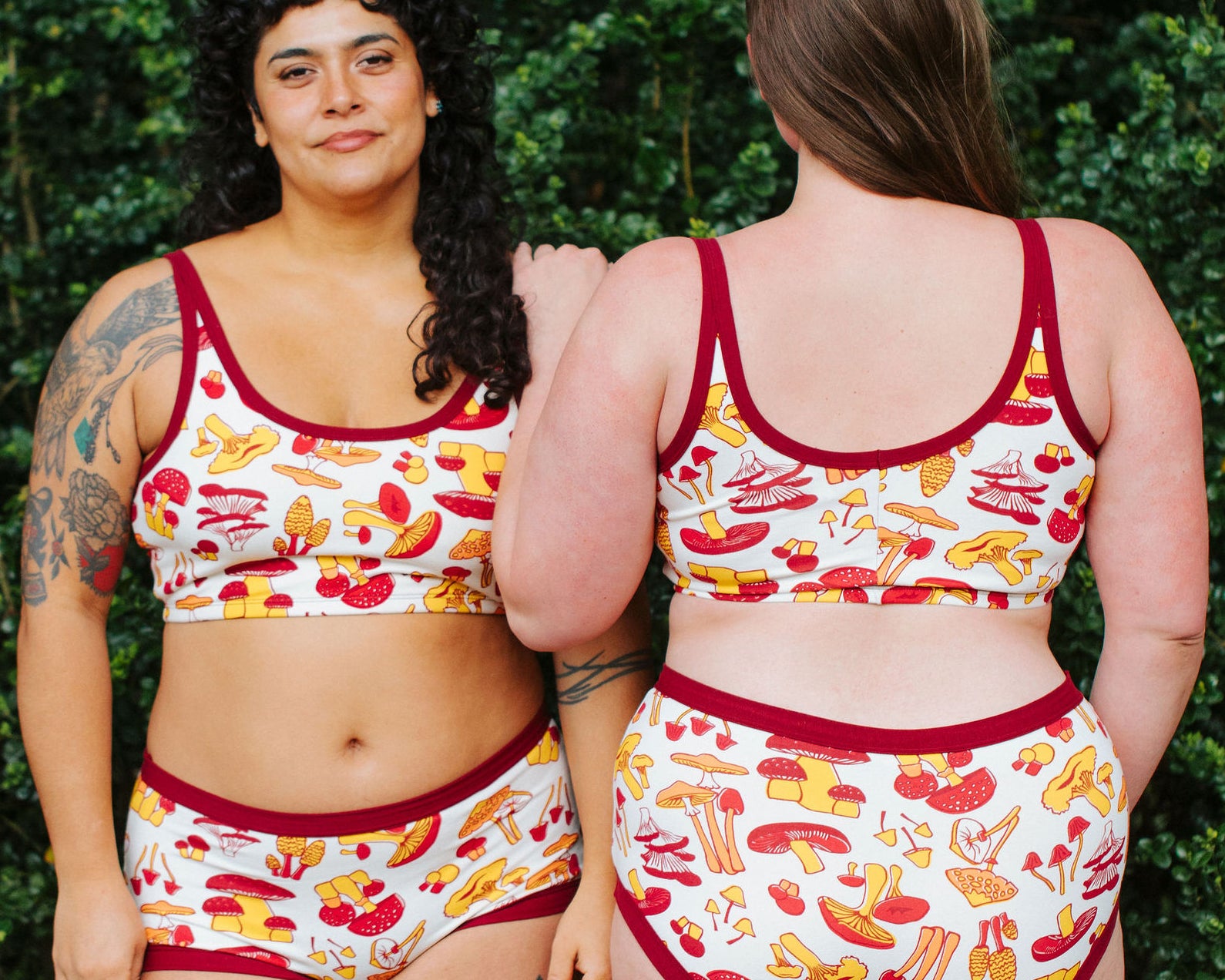Two models wearing Thunderpants Longline Bras and underwear in Whadda Fungi - red, yellow, and orange mushroom print.