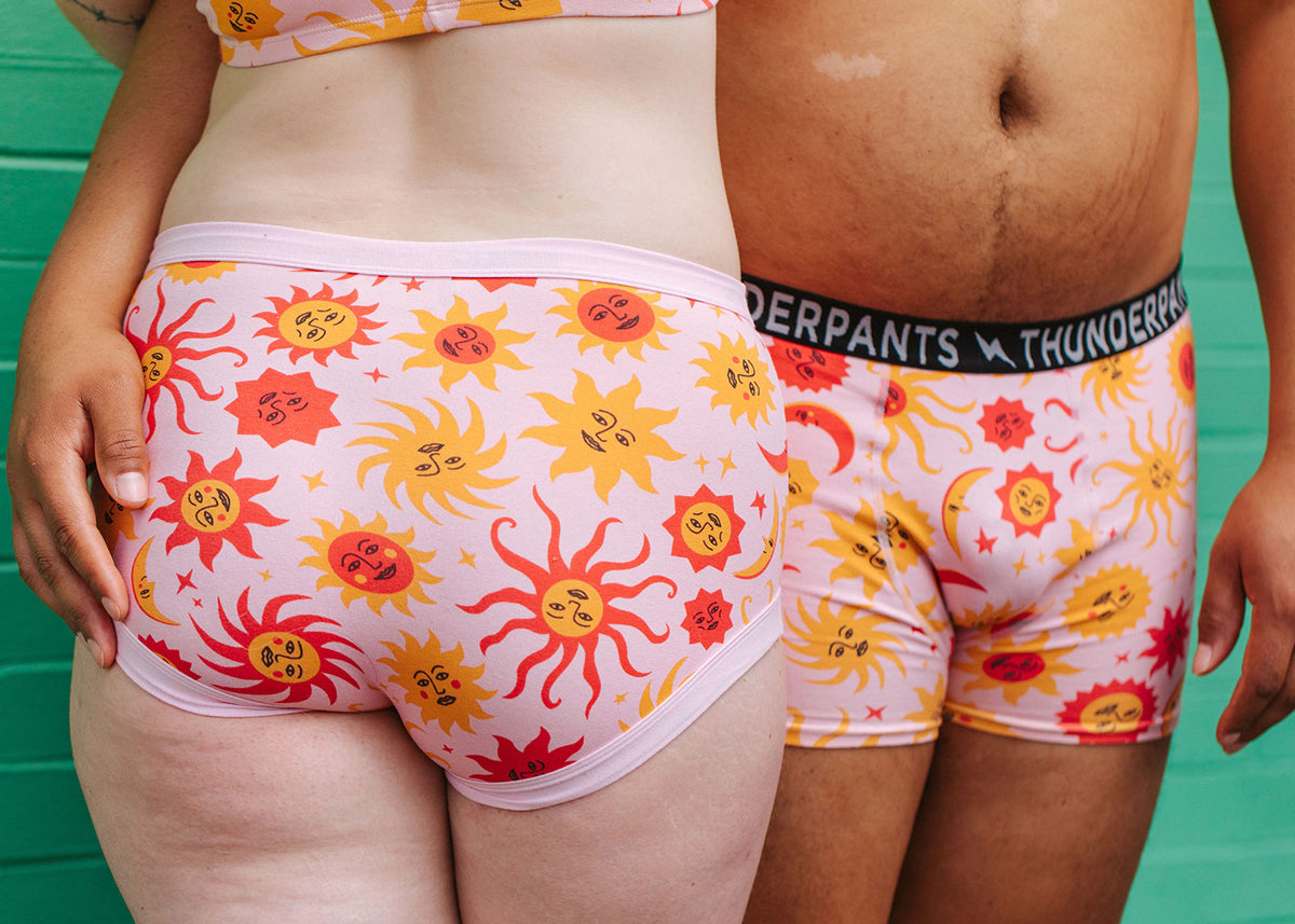 Two models wearing Thunderpants Original and Boxer Brief style underwear in Luna y Sol print - pink with orange and red suns and moons. 