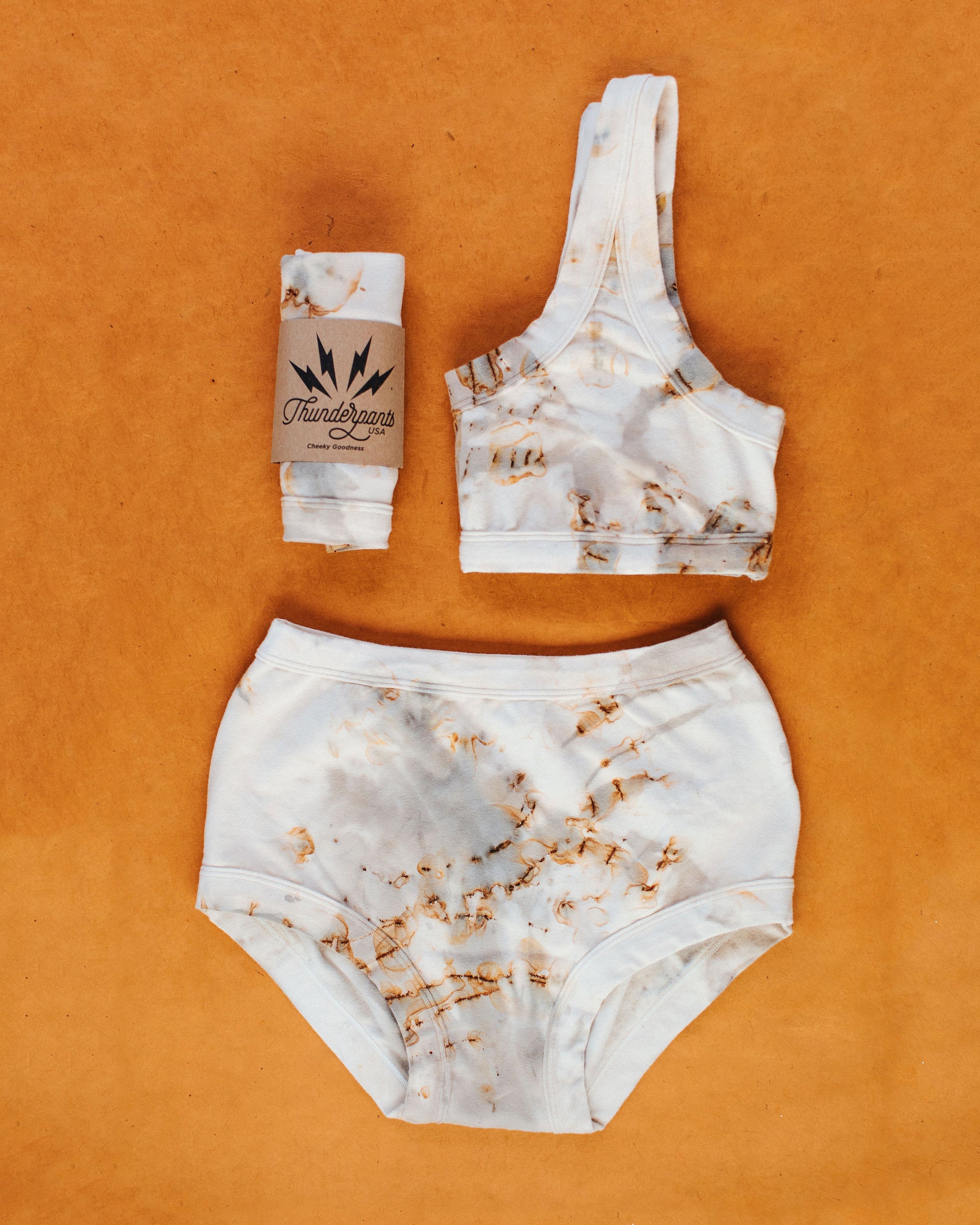 Flat lay photo of Thunderpants Bralette and Sky Rise style underwear in Mineral Rust Hand Dye.
