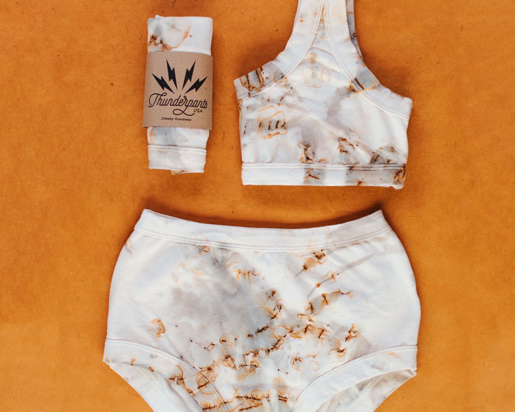 Flat lay of Thunderpants Original style underwear and Bralette in Mineral Rust Dye.