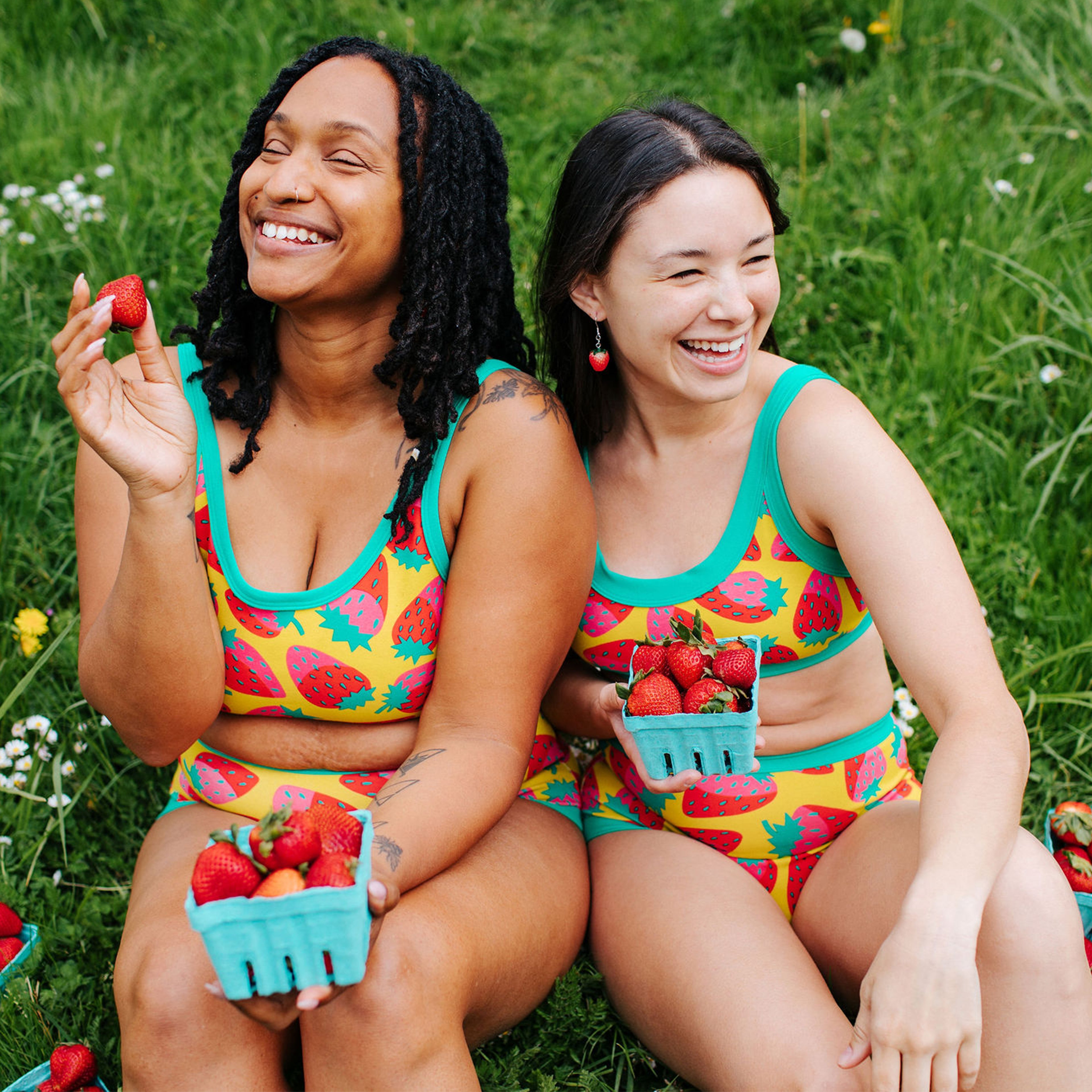 Two models smiling while wearing sets in Thunderpants Strictly Strawberry print - pink, red, and peacock green.