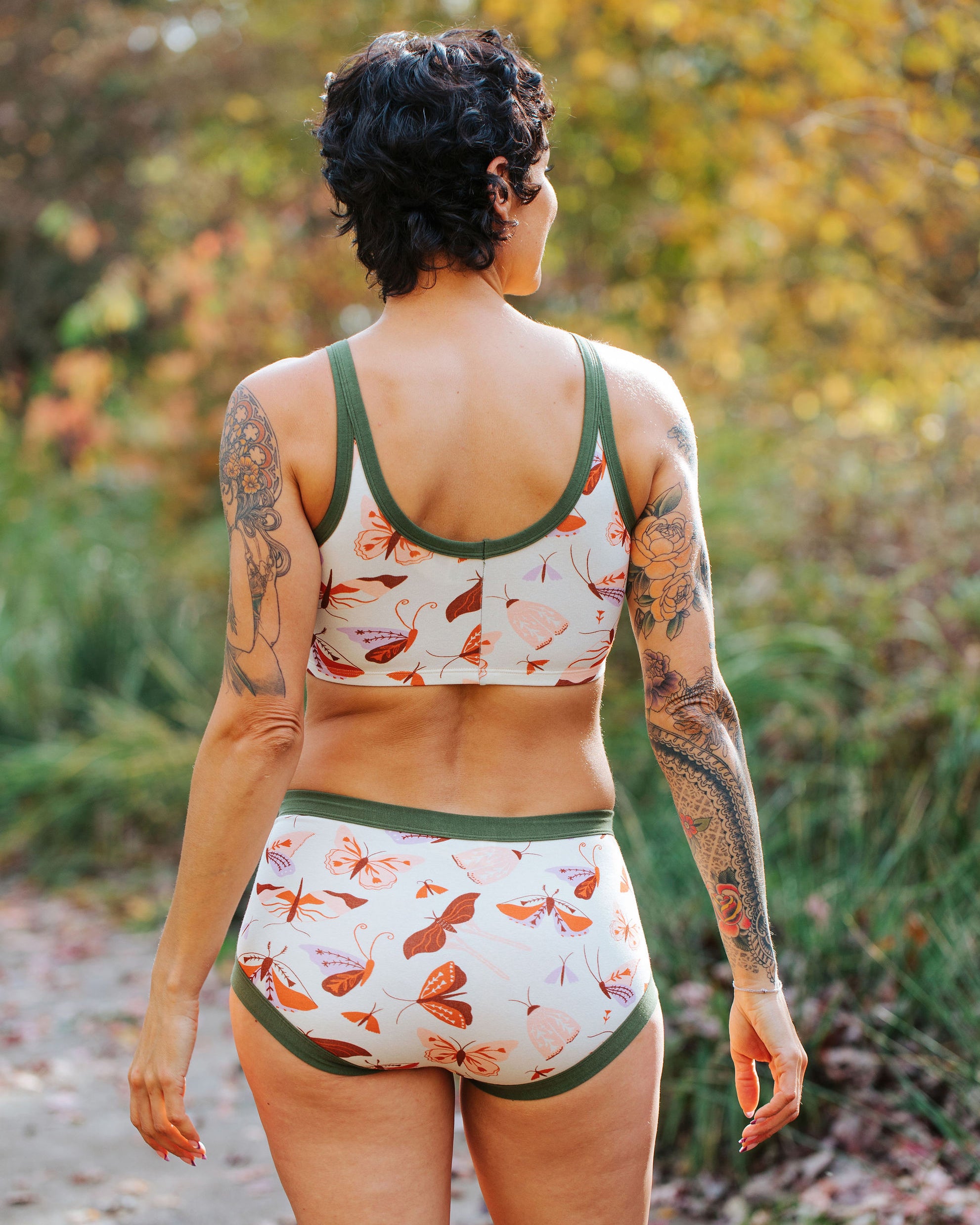 Model wearing Thunderpants Original style underwear and Longline Bra in Field Study: a moth print in red, orange, pink, and purple bound in green.