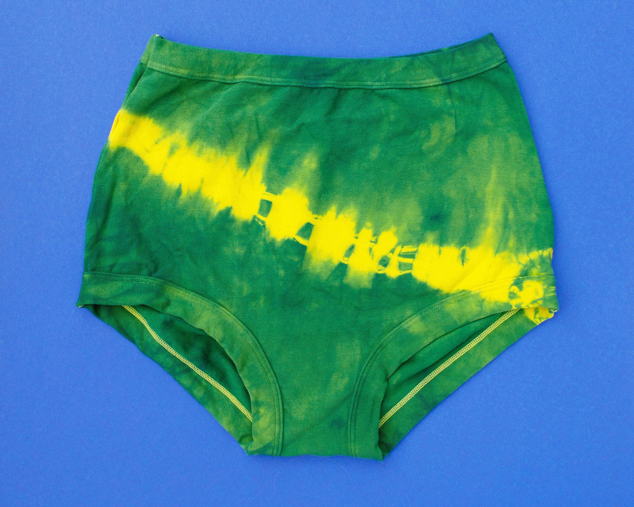 Flat lay of Thunderpants Sky Rise style underwear in Lightning Bolt hand dye - blue/green with yellow stripe.
