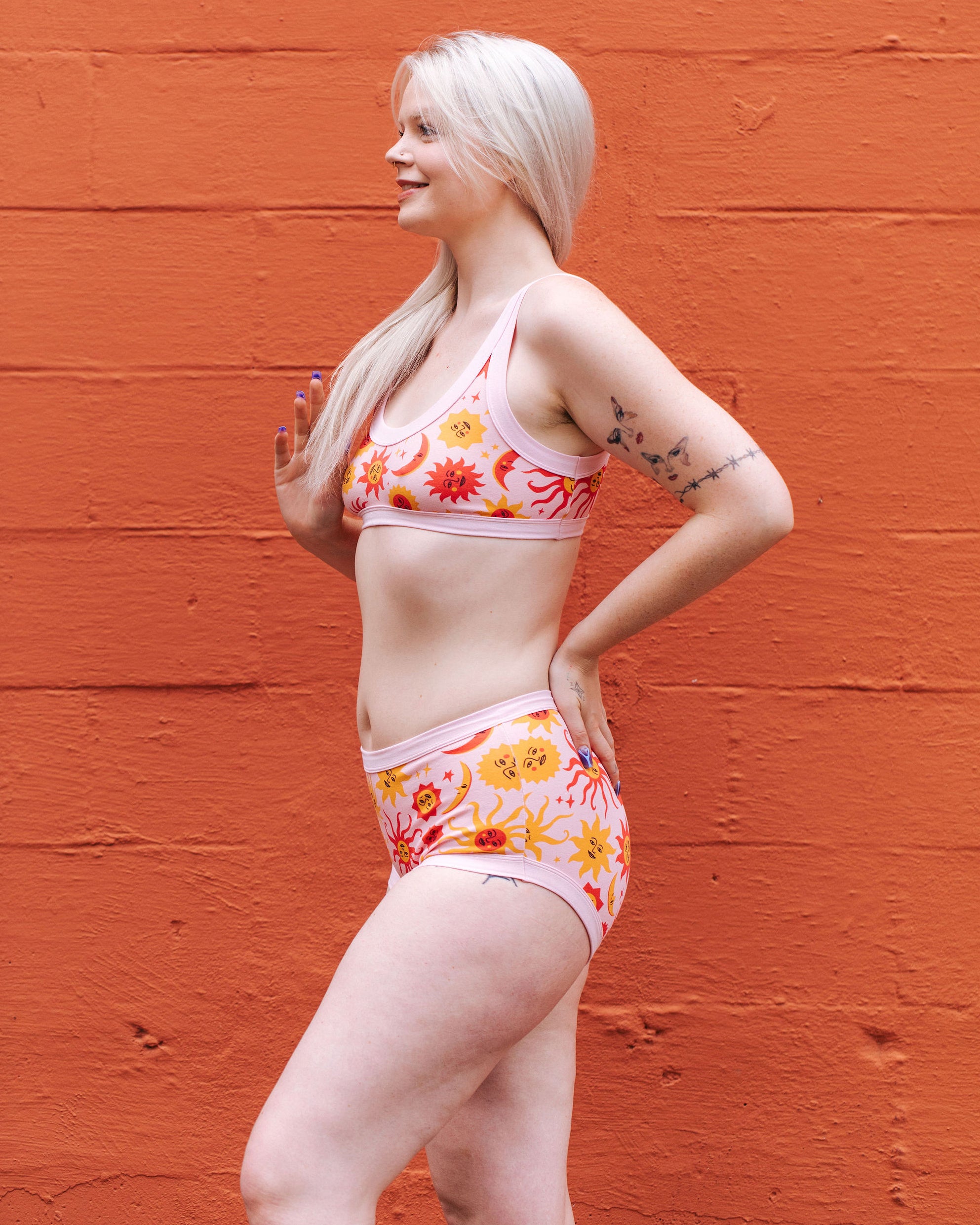 Model wearing Thunderpants Original style underwear and Bralette in Luna Y Sol print - pink, yellow, and orange suns and moons.