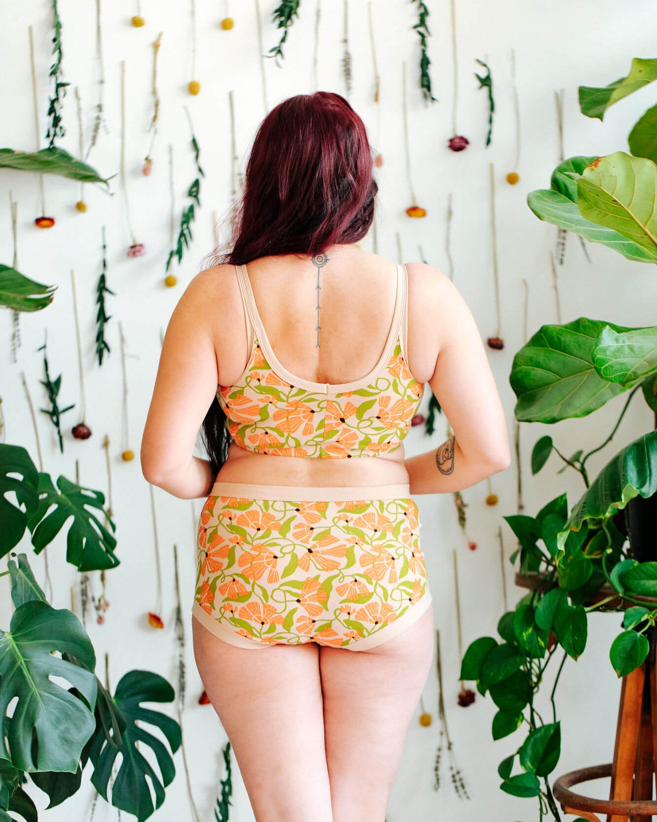 Model wearing a set of Thundrpants Longline Bra and Original style underwear in Secret Garden - orange flowers and green leaves.