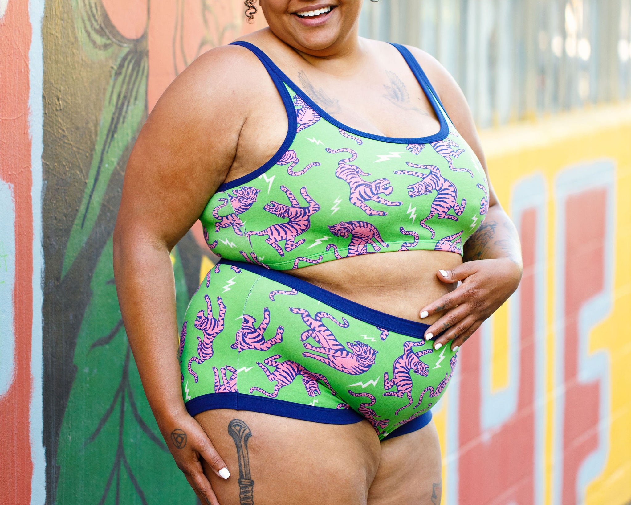 Model wearing Thunderpants organic cotton Original style underwear and Longline Bra in Electric Tiger - green with pink and blue tigers and white lightning bolts.