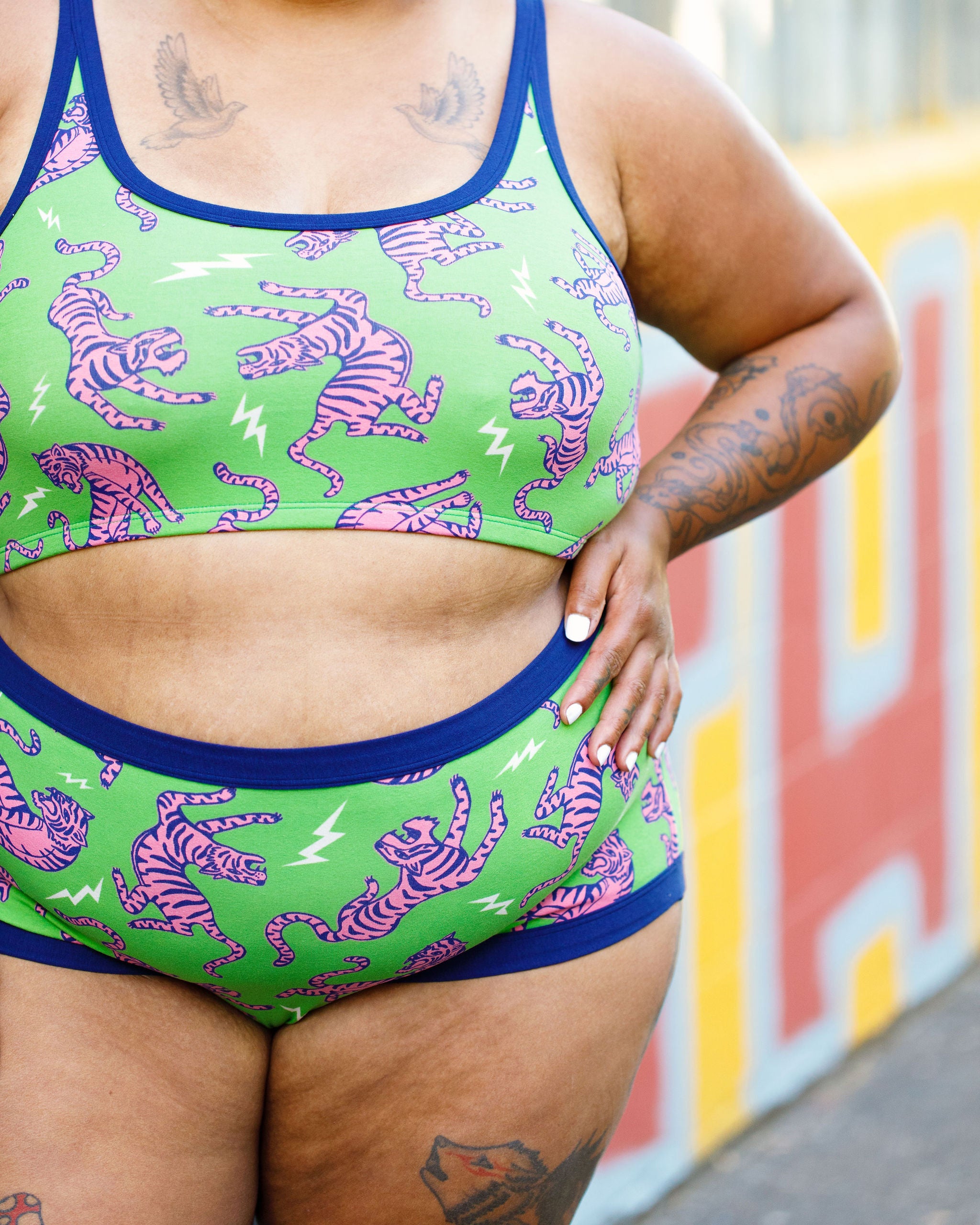 Model wearing Thunderpants organic cotton Original style underwear and Longline Bra in Electric Tiger - green with pink and blue tigers and white lightning bolts.