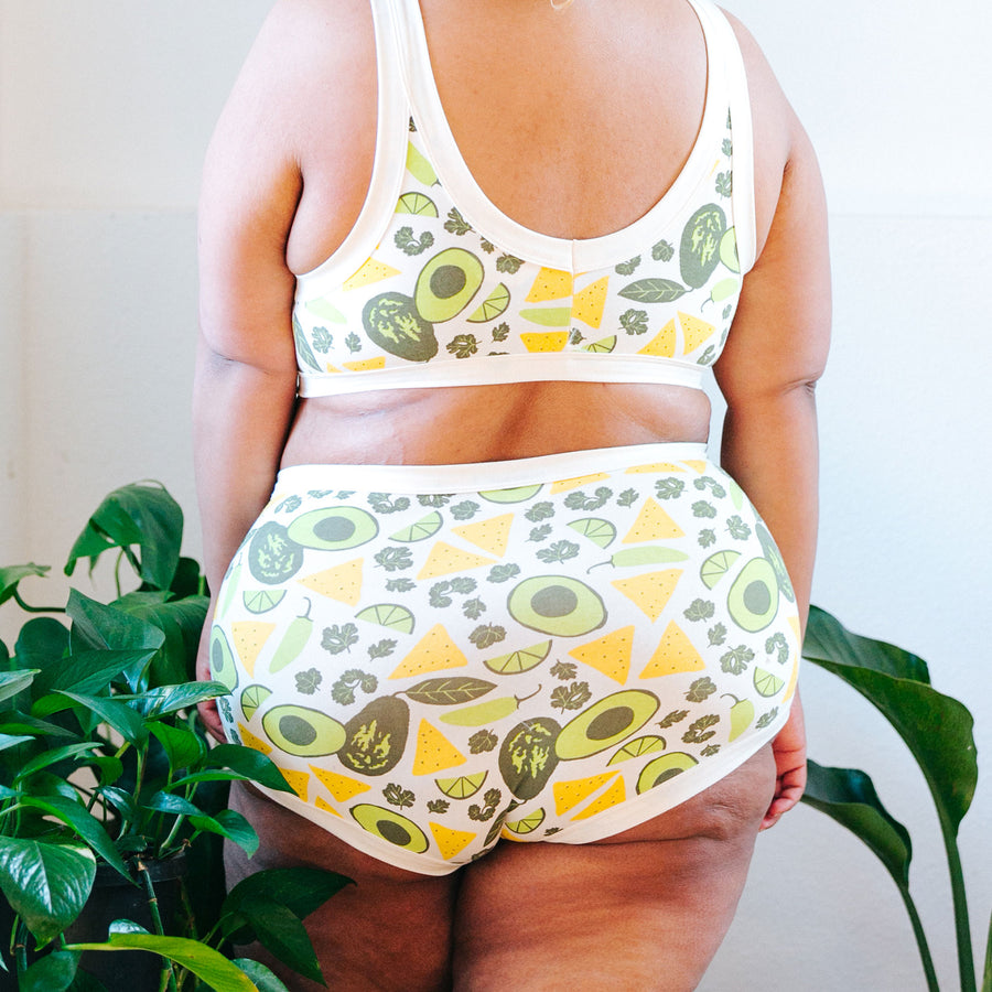Model with her back to us wearing Thunderpants Organic Cotton Original underwear and Bralette in our Party Guac print: yellow chips, green avocados, limes, and cilantro.