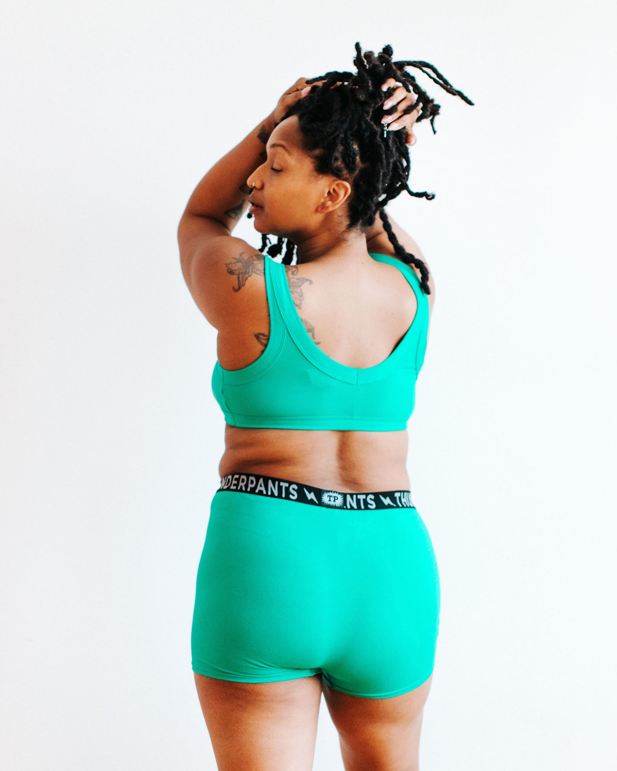 Model wearing Thunderpants Bralette and Boxer Brief style underwear in Peacock Green.