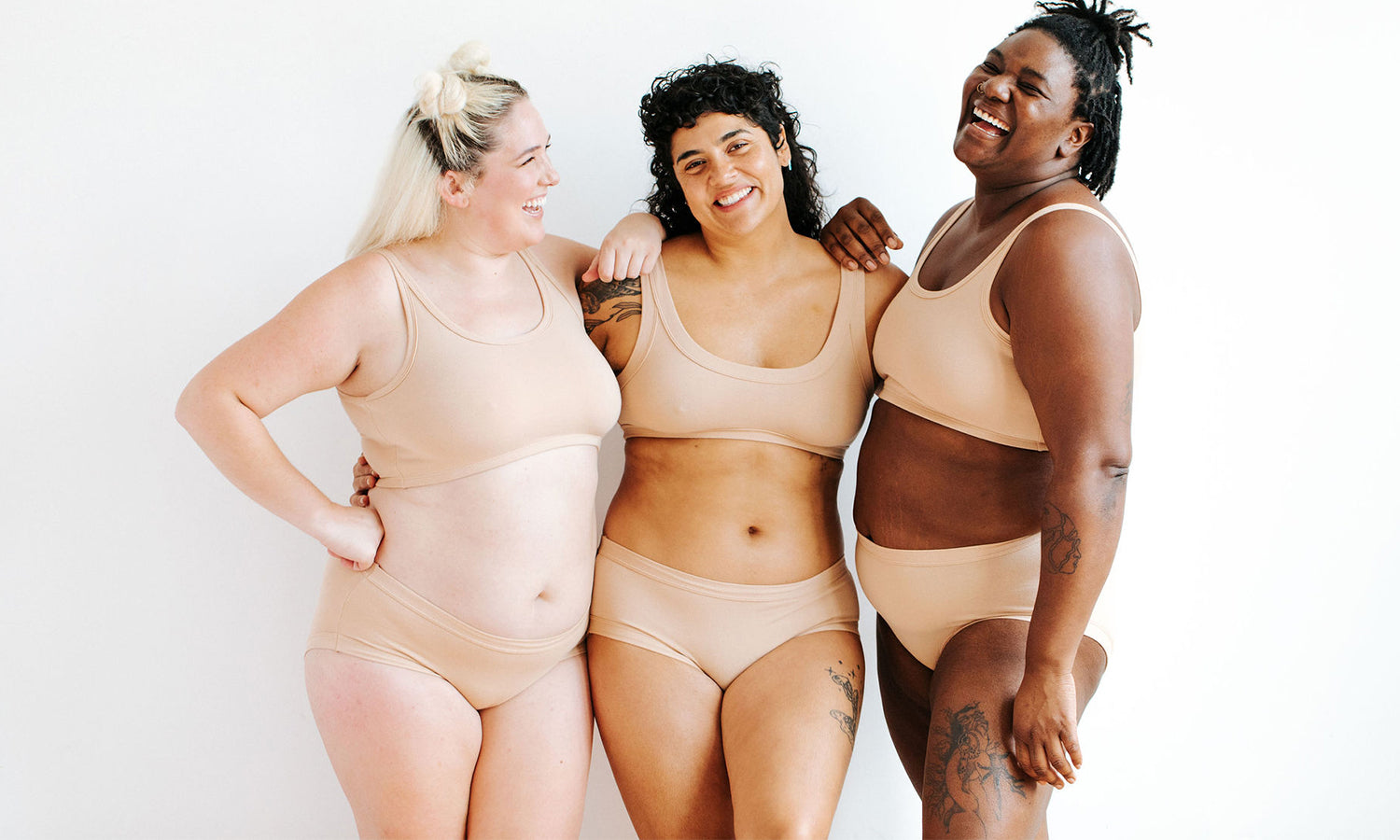 Three models wearing Thunderpants Hipster style underwear and Bras in Pine Nut - lighter tan color. 