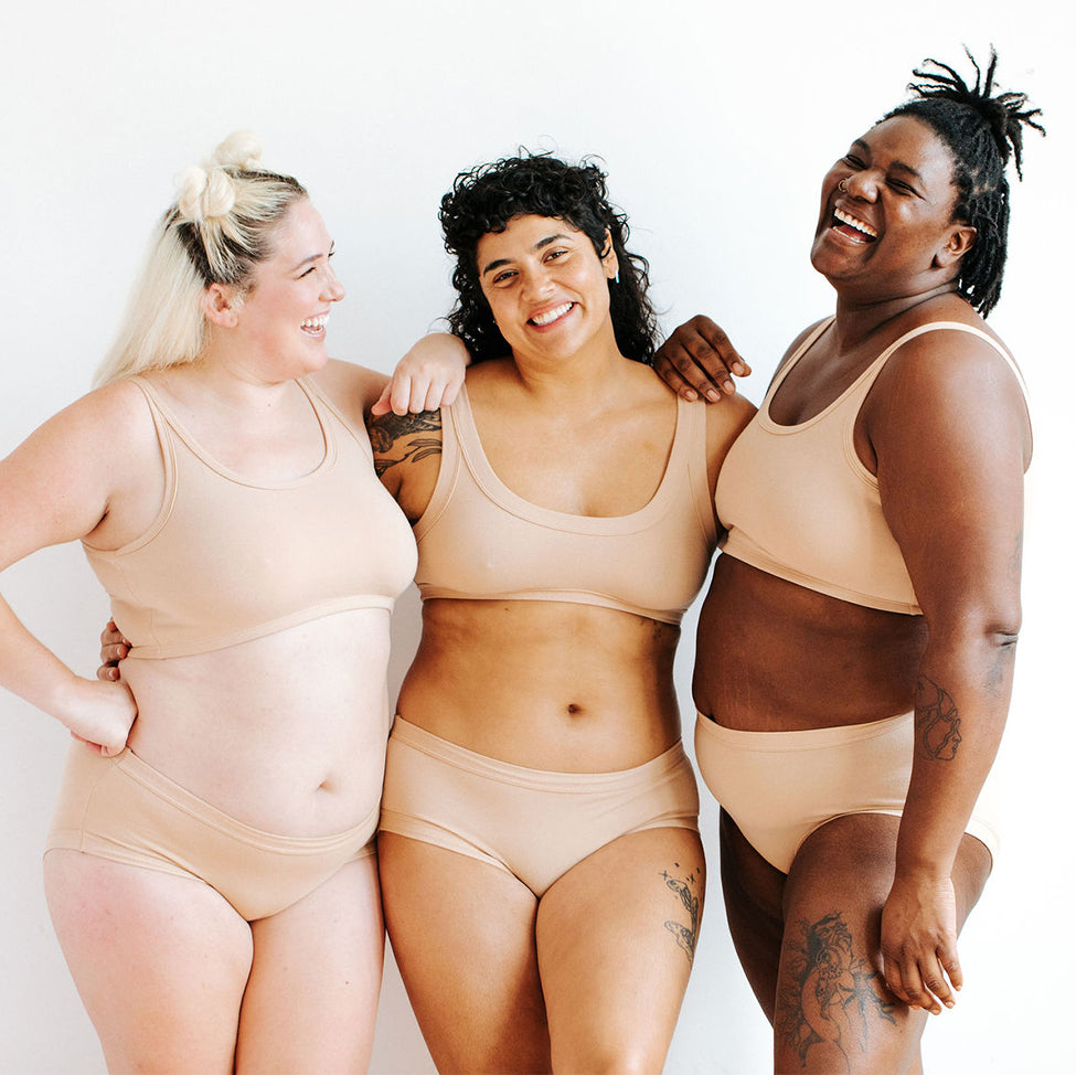 Three models wearing Thunderpants Hipster style underwear and Bras in Pine Nut - lighter tan color. 