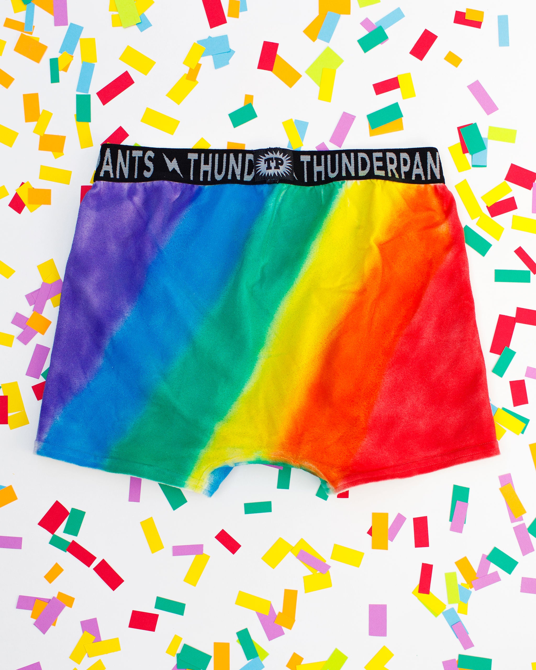 Thunderpants organic cotton Boxer Brief style underwear in hand painted rainbow stripes for Pride laying on rainbow confetti.