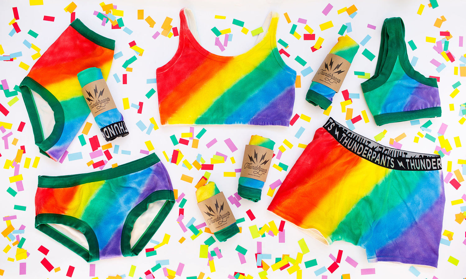 Flat lay of Thunderpants organic cotton products in many styles in the Pride Philanthropants hand painted rainbow print.