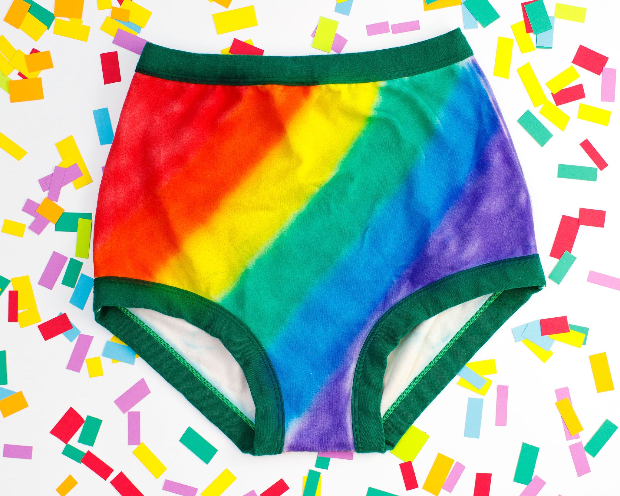 Thunderpants organic cotton Sky Rise style underwear in hand painted rainbow stripes for Pride laying on rainbow confetti.