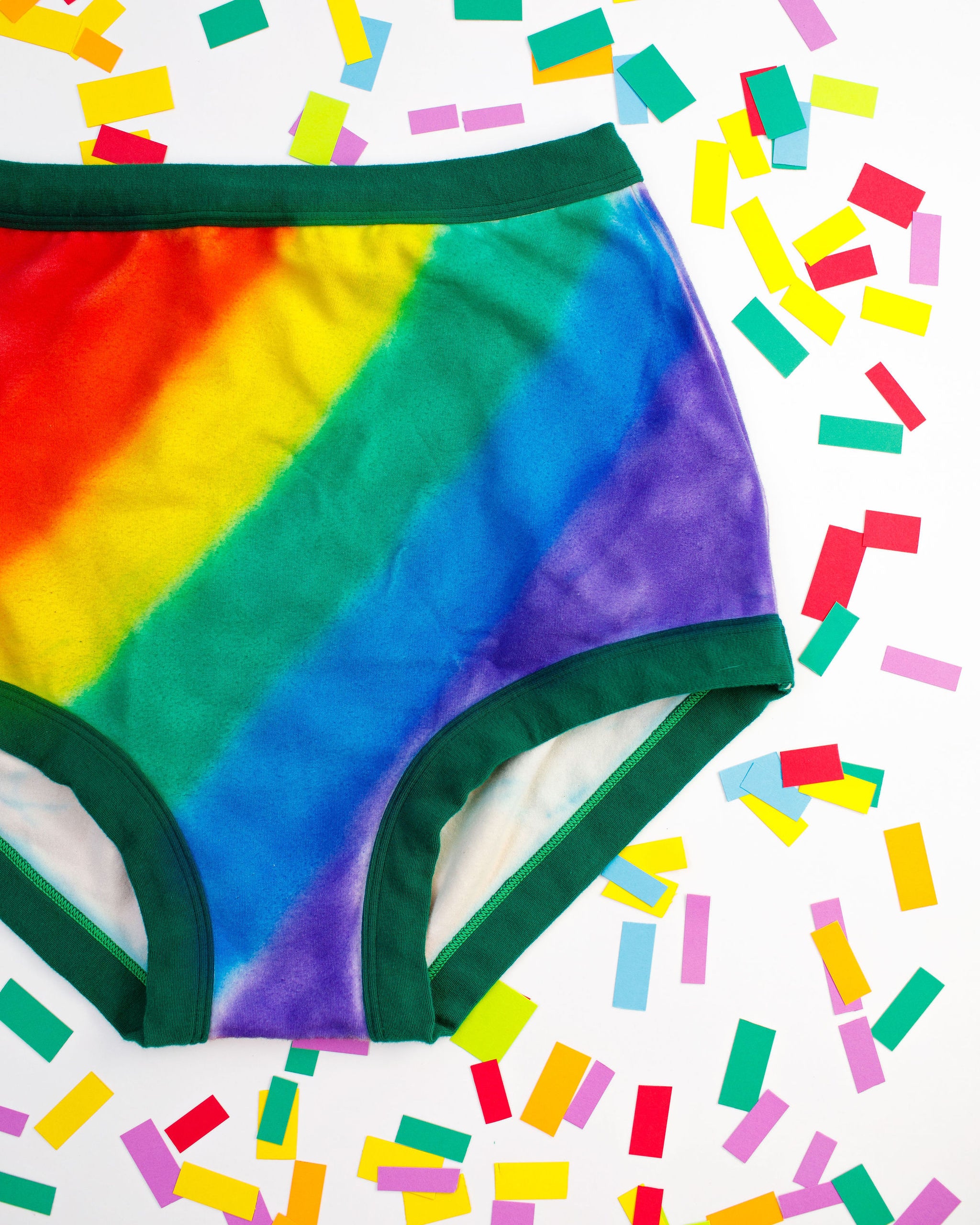 Thunderpants organic cotton Sky Rise style underwear in hand painted rainbow stripes for Pride laying on rainbow confetti.