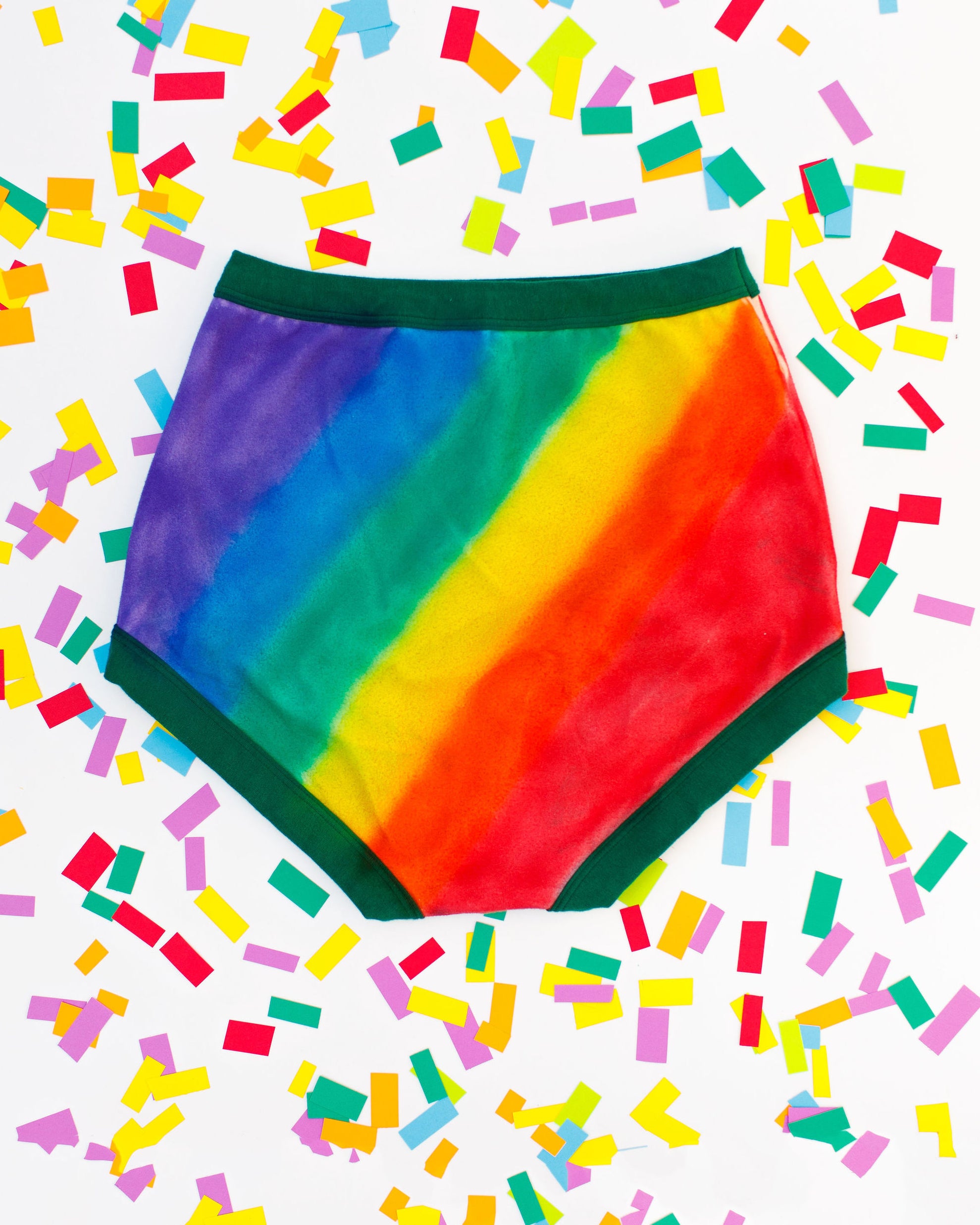 Thunderpants organic cotton Sky Rise style underwear in hand painted rainbow stripes for Pride laying on rainbow confetti.
