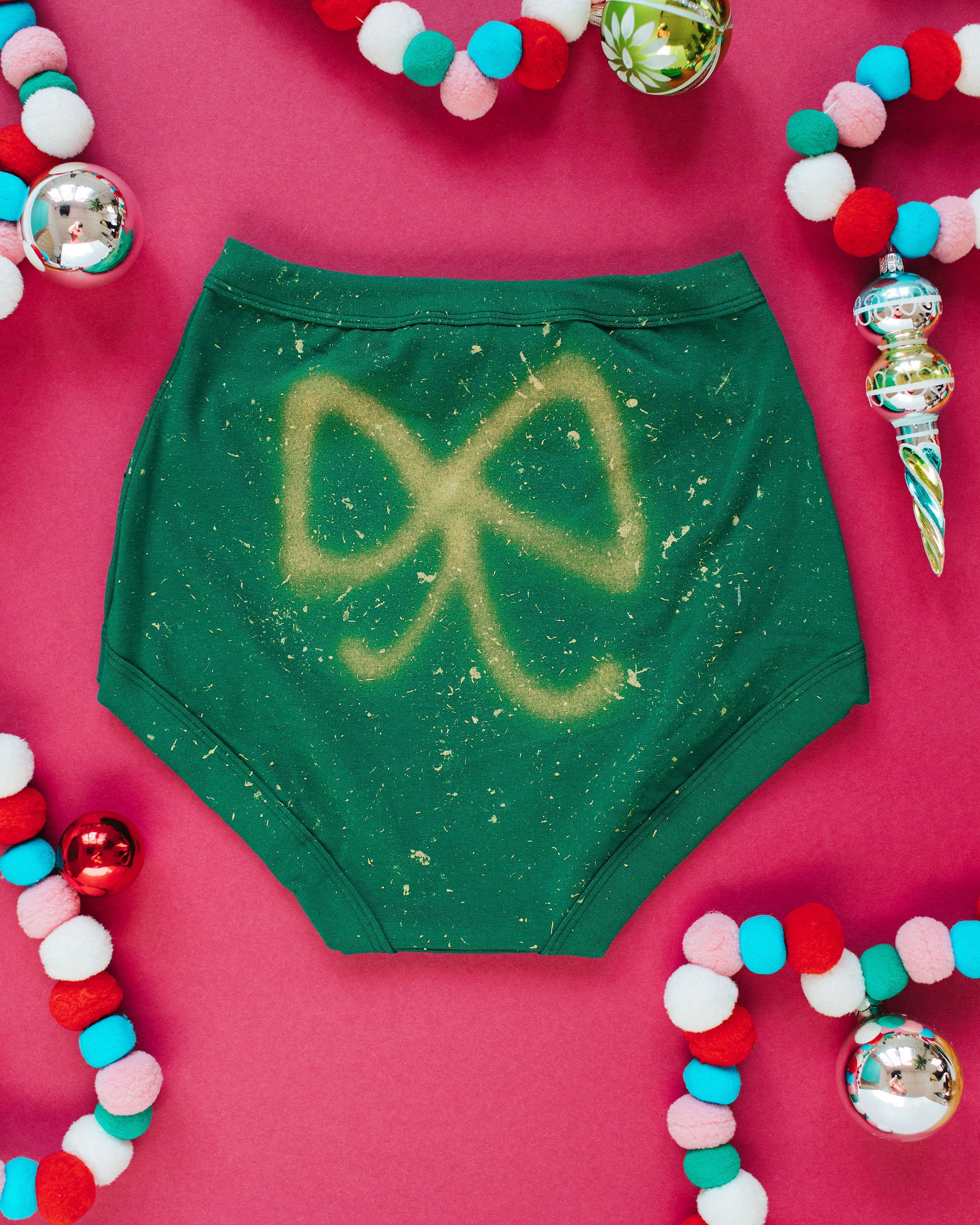 Flat lay of Thunderpants Sky Rise style underwear in Put a Bow on It: hand painted gold bow.