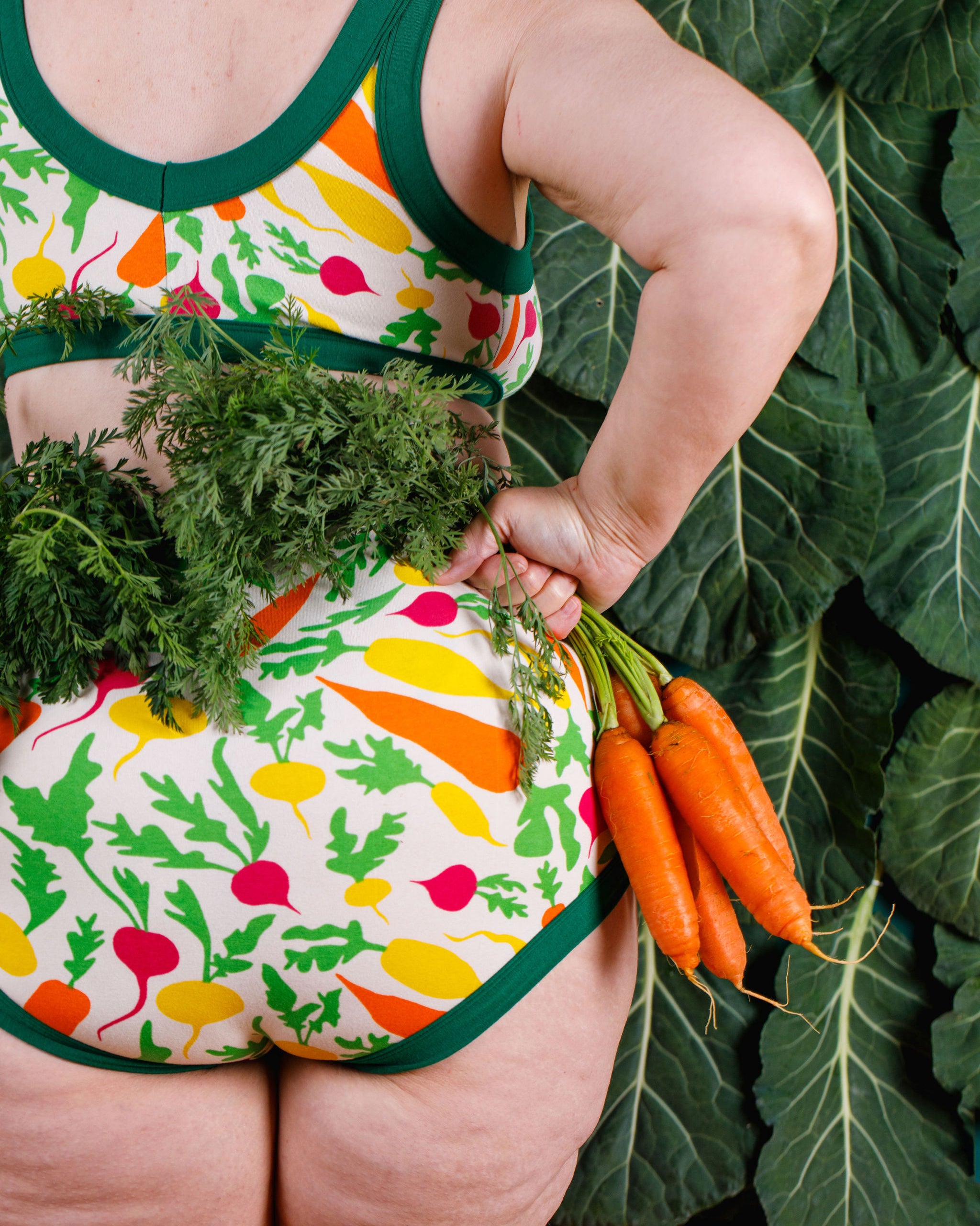 Close up of model wearing Thunderants Sky Rise style underwear and matching Bralette in Root Veggies print - yellow, orange, pink, and green vegetables.