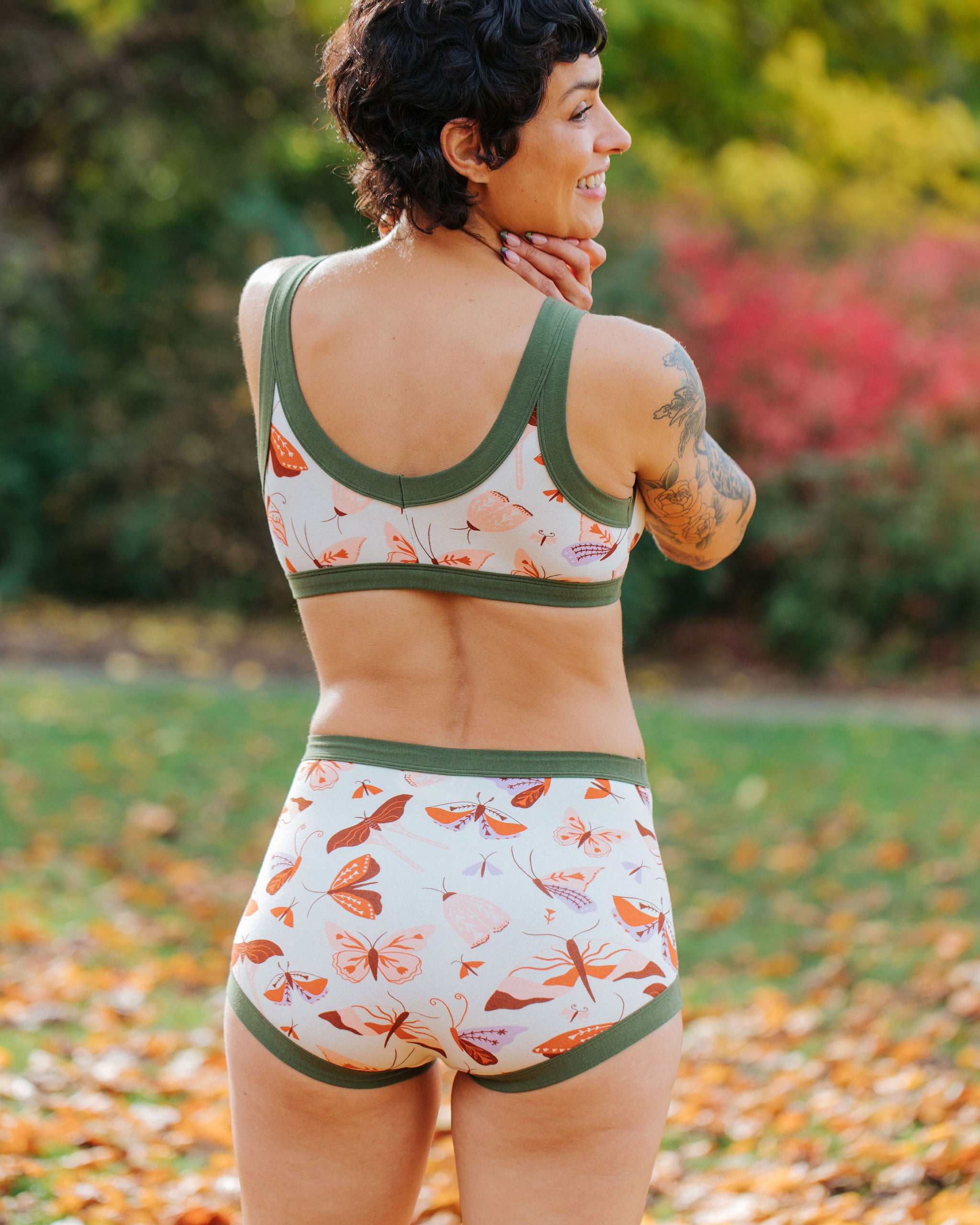 Model wearing Thunderpants Sky Rise style underwear and Bralette in Field Study: a moth print in red, orange, pink, and purple bound in green.