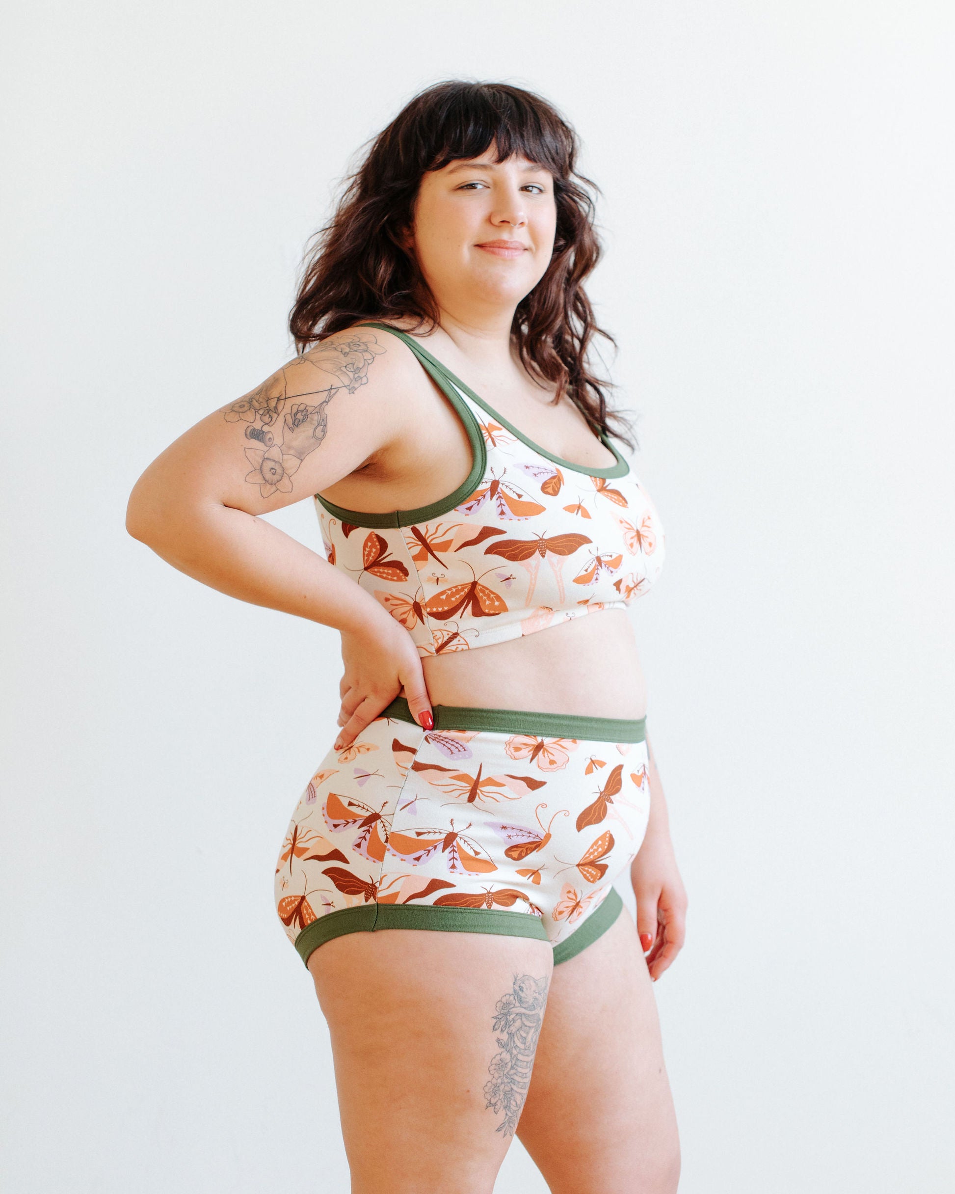 Model wearing Thunderpants Sky Rise style underwear and Longline Bra in Field Study: a moth print in red, orange, pink, and purple bound in green.