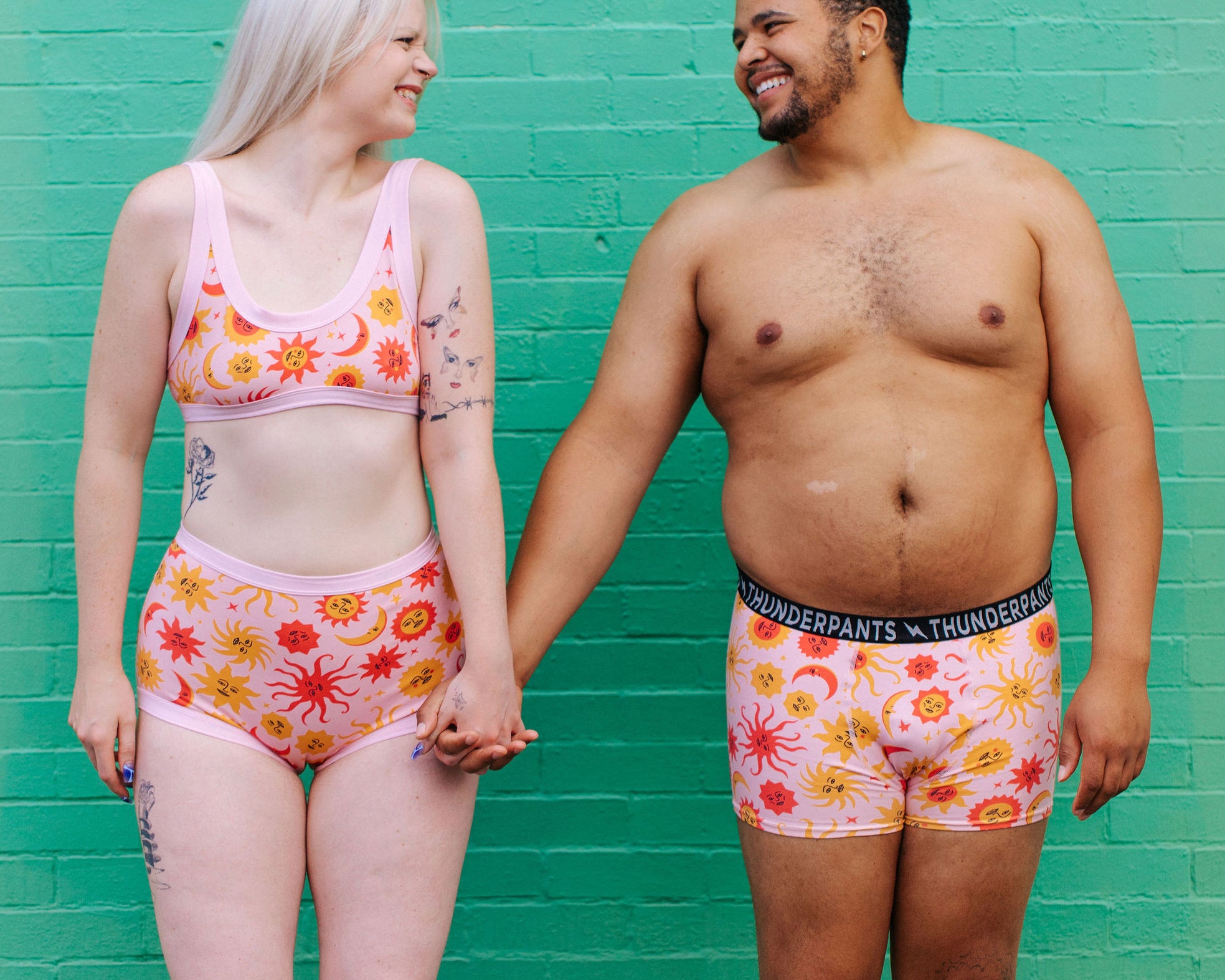 Two models wearing Thunderpants Sky Rise style underwear and Boxer Brief style underwear in Luna y Sol print - pink, yellow, and orange suns and moons.