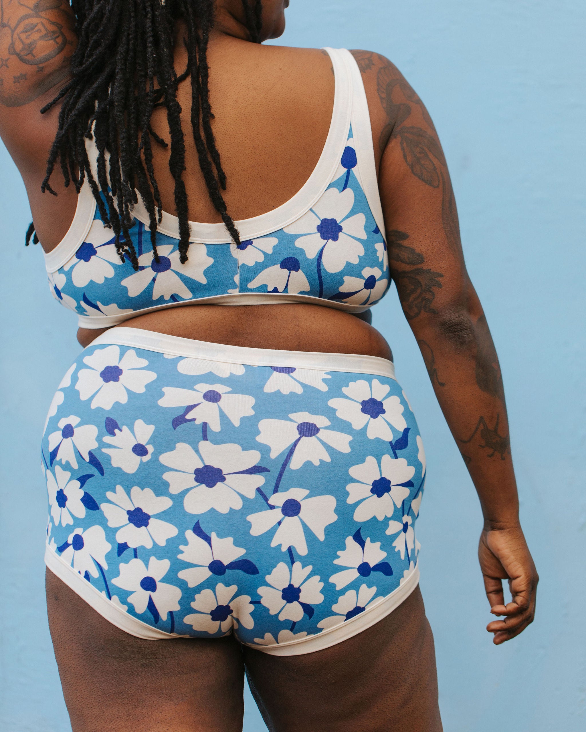 Model wearing Thunderpants Sky Rise style underwear and Bralette in Moody Blooms - white and blue flowers with blue background.