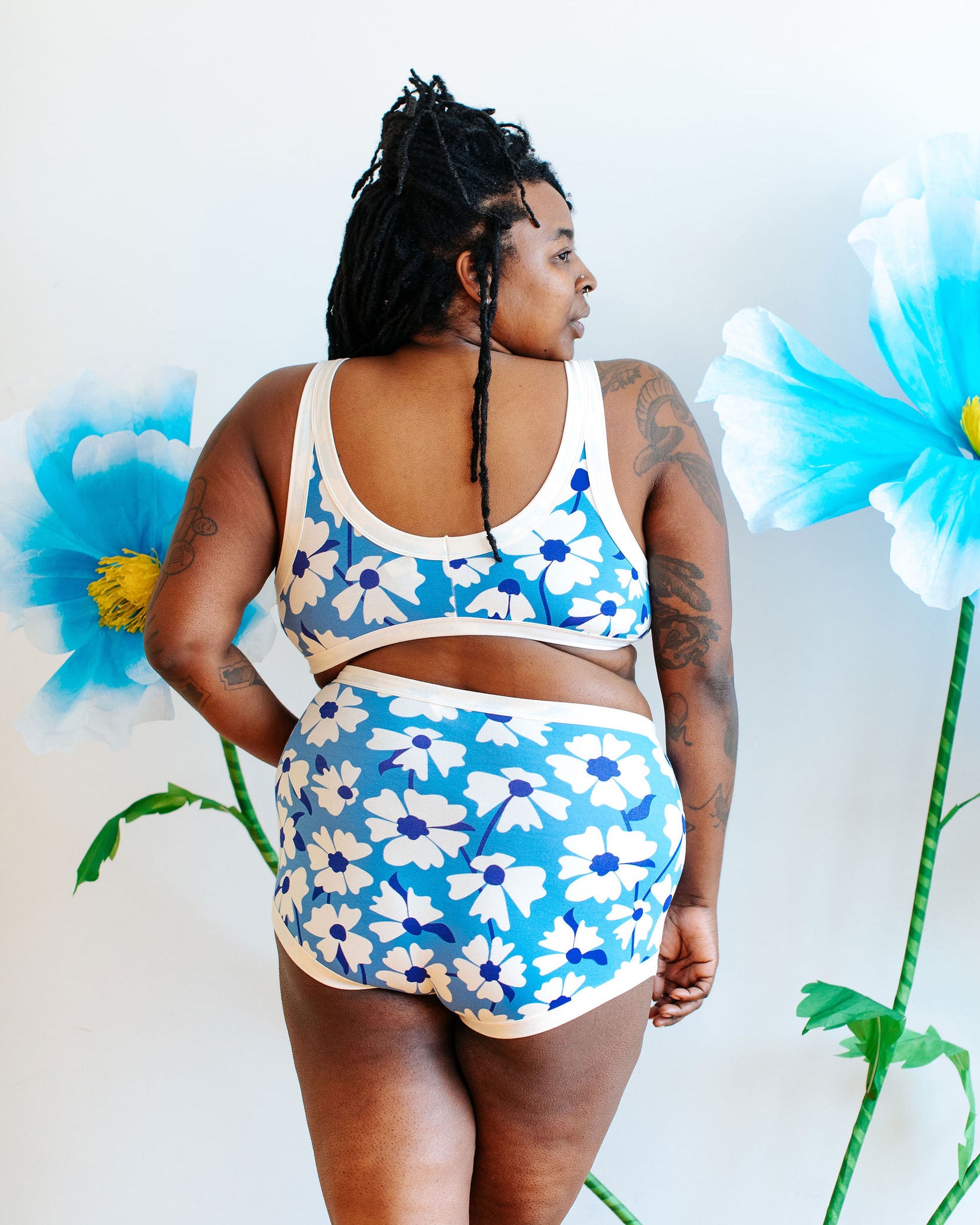Model wearing Thunderpants Sky Rise style underwear and Bralette in Moody Blooms - white and blue flowers with blue background.