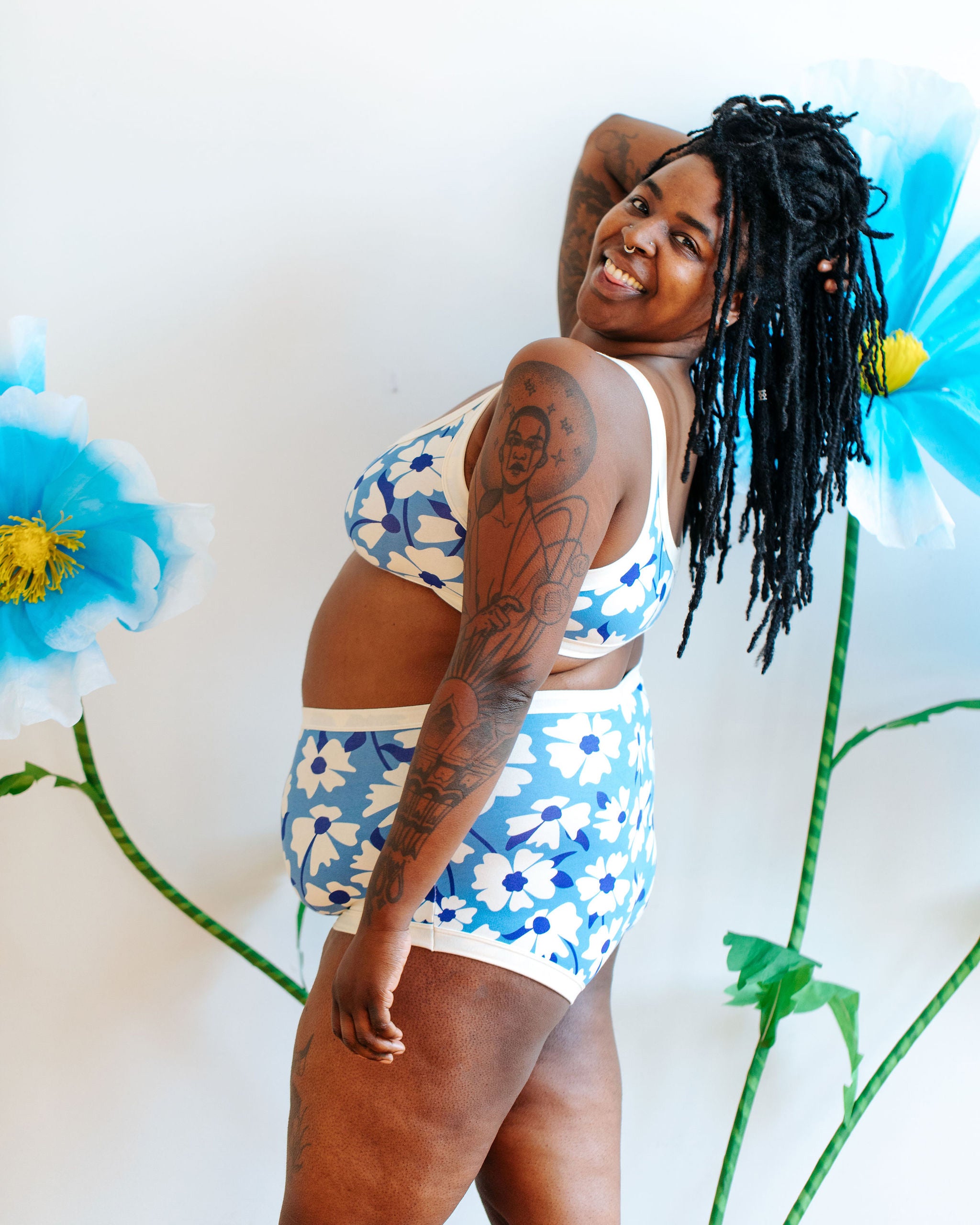 Model wearing Thunderpants Sky Rise style underwear and Bralette in Moody Blooms - white and blue flowers with blue background.