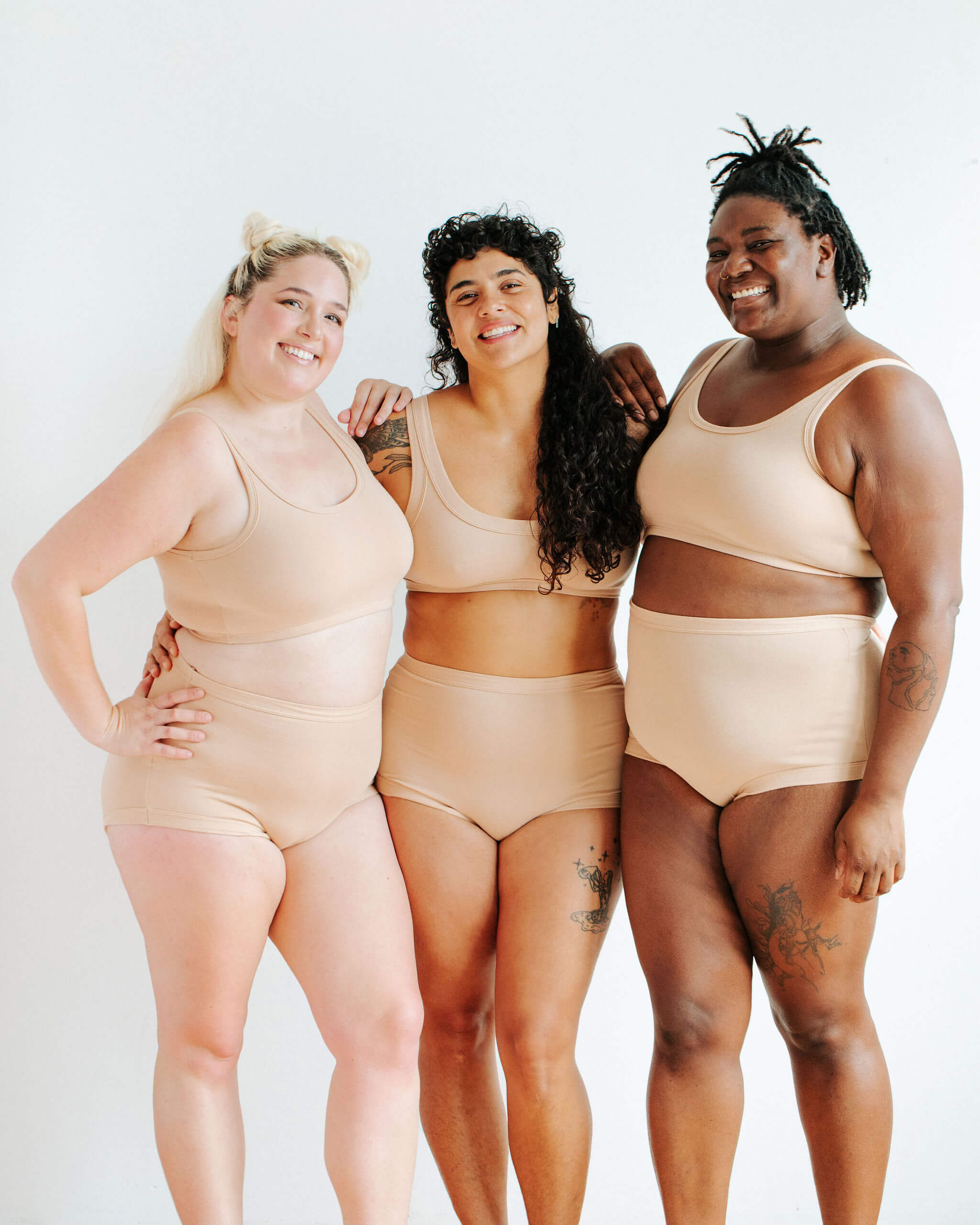 Three models wearing Thunderpants Sky Rise style underwear and Bras in Pine Nut - lighter tan color.