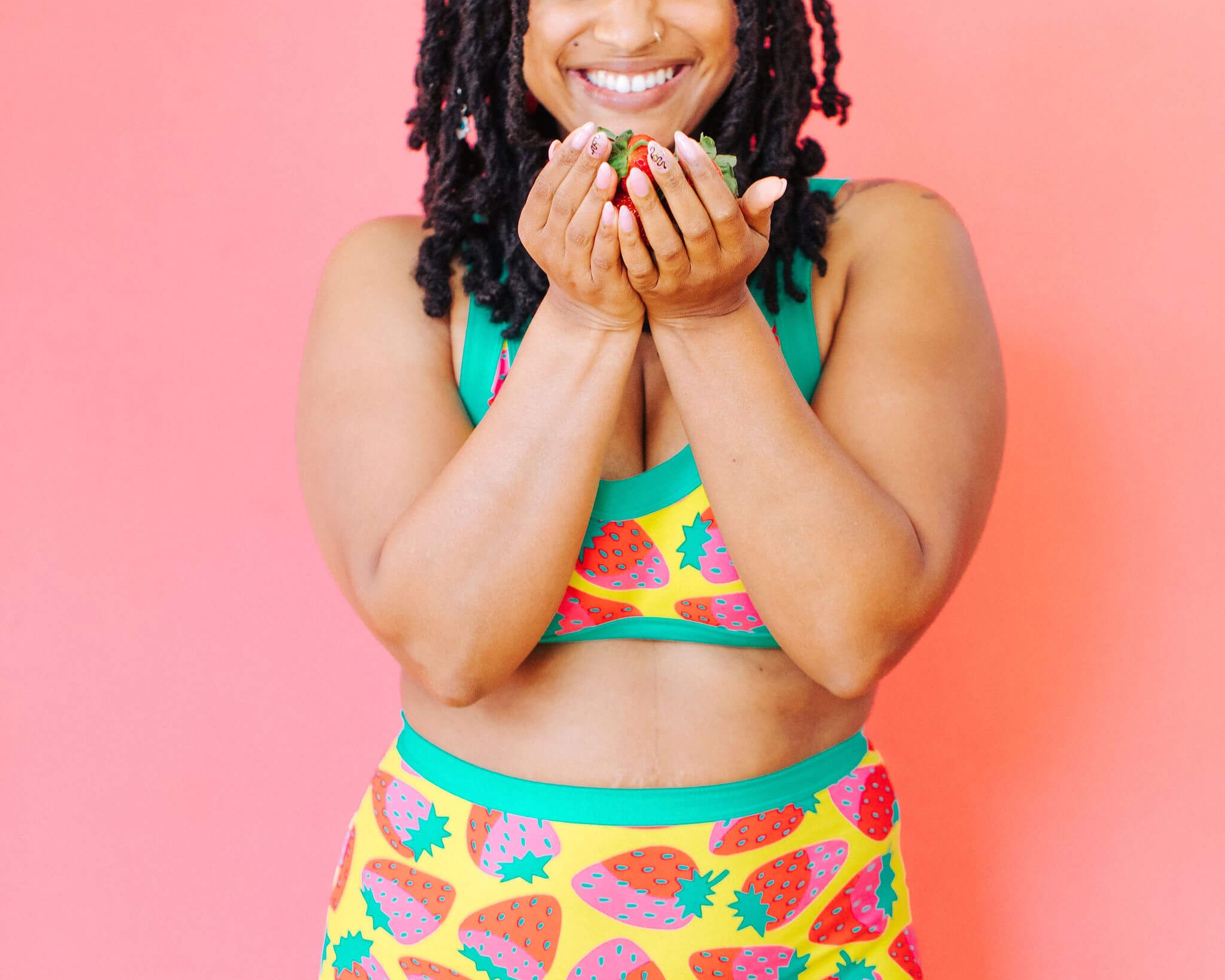 Model wearing Thunderpants Sky Rise style underwear and Bralette in a Strawberry print - pink, red, and peacock green on chartreuse. 