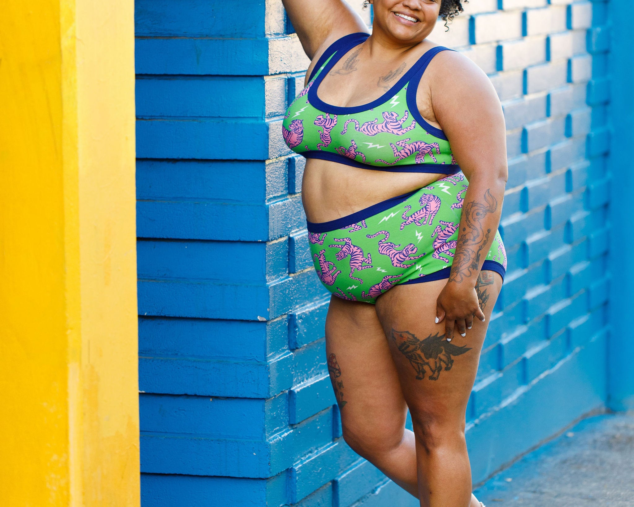 Model wearing Thunderpants organic cotton Sky Rise style underwear and Bralette in Electric Tiger - green with pink and blue tigers and white lightning bolts.