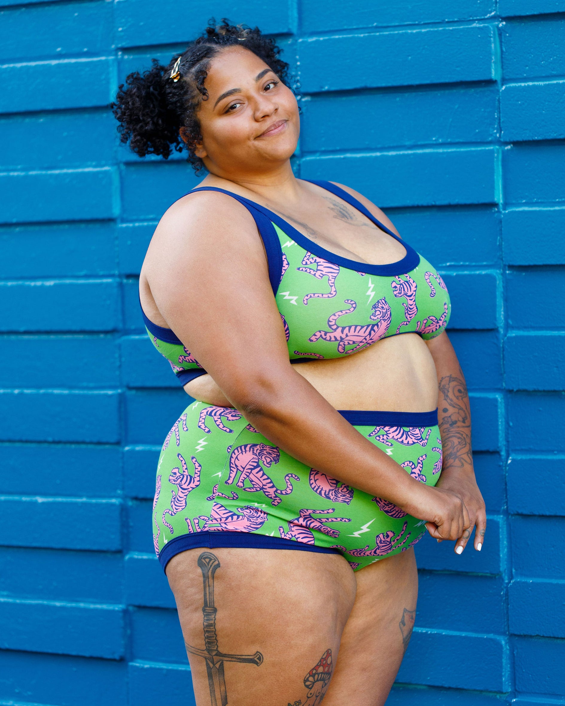 Model wearing Thunderpants organic cotton Sky Rise style underwear and Bralette in Electric Tiger - green with pink and blue tigers and white lightning bolts.