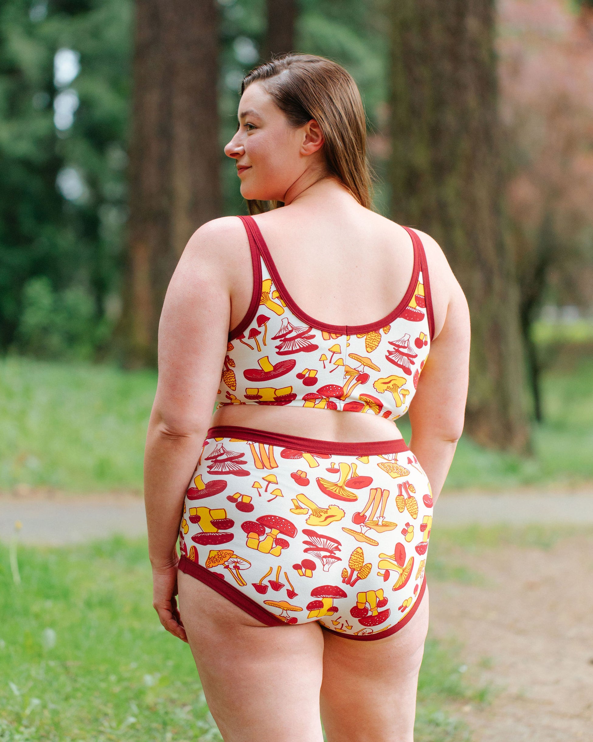 Model wearing Thunderpants Sky Rise style underwear and Bralette in Whadda Fungi print - red, yellow, and orange mushroom print.